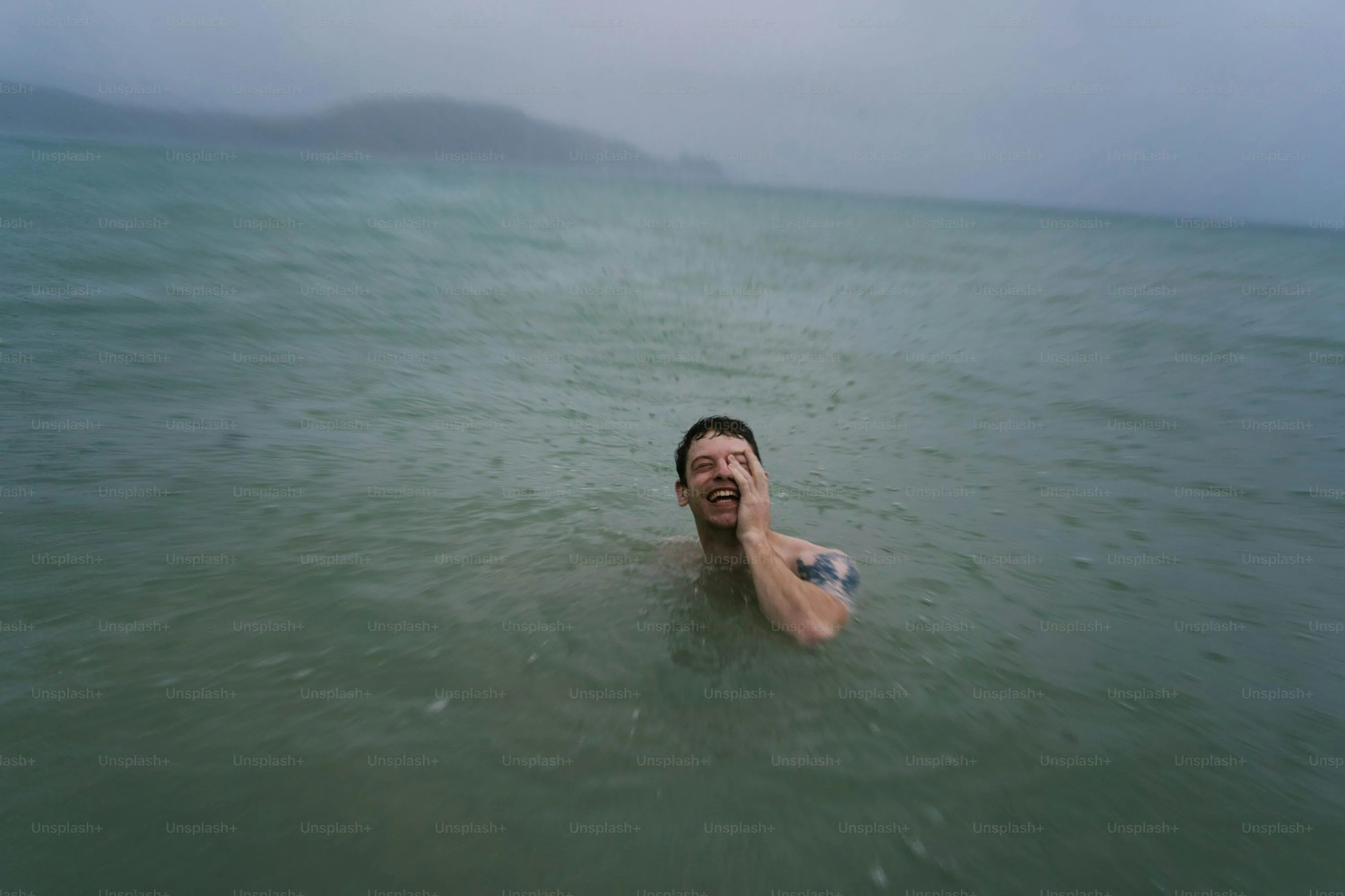 Single Swan Floating on Lake Under Grey Rainy Sky