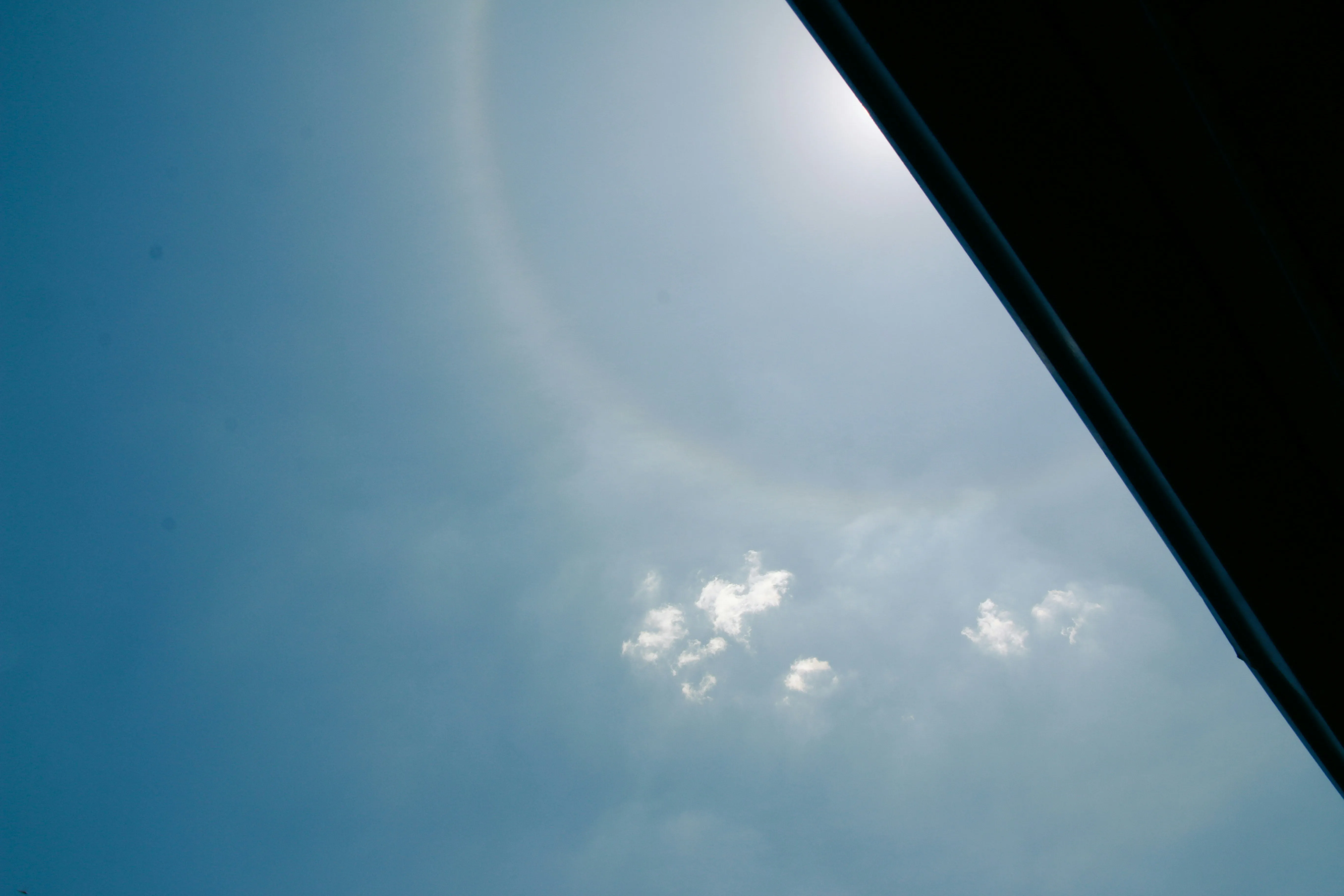 Sky Viewed From Aircraft Window with Halo Sun and Clouds