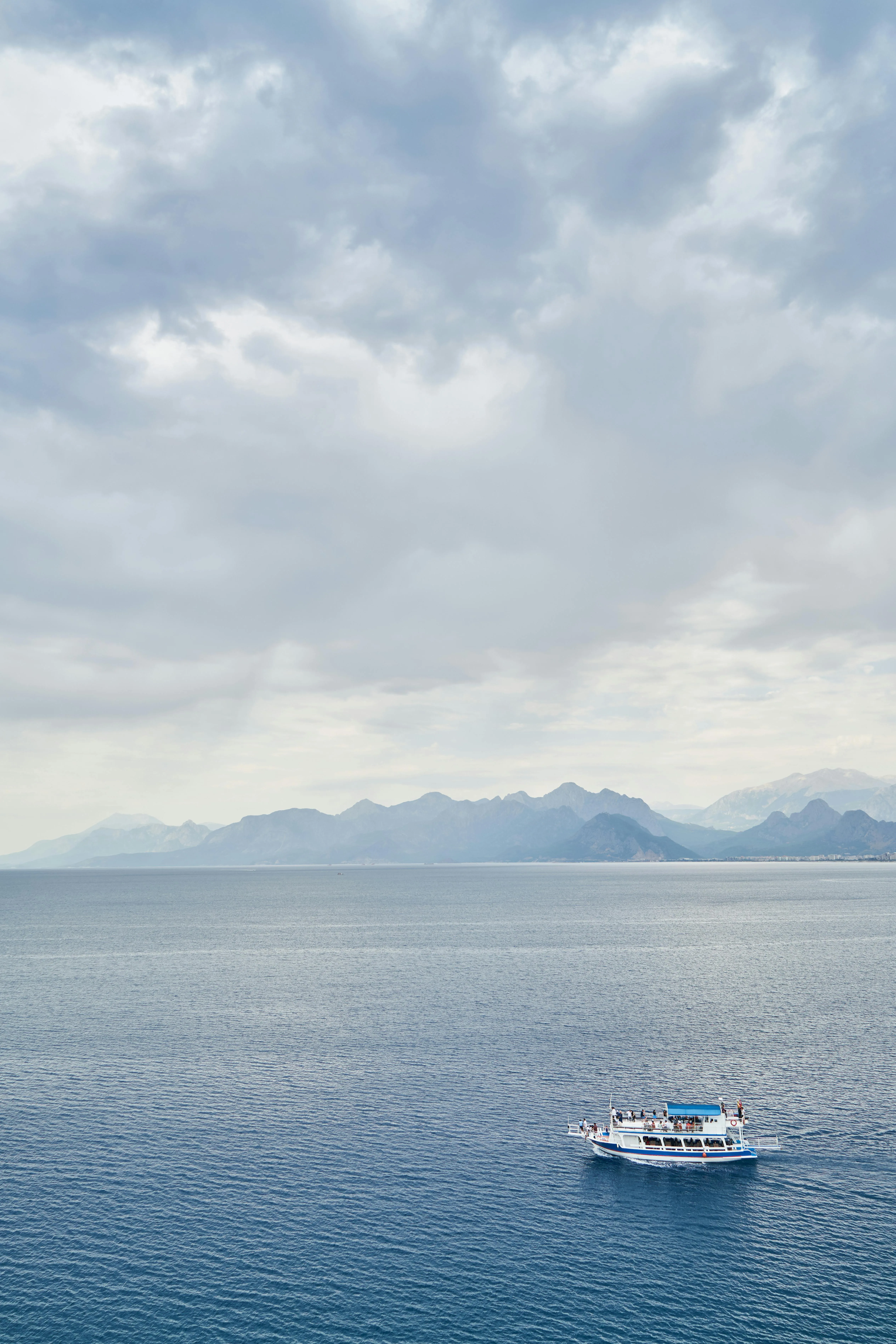 Small Boat on Still Ocean with Hazy Sky and Distant Hills