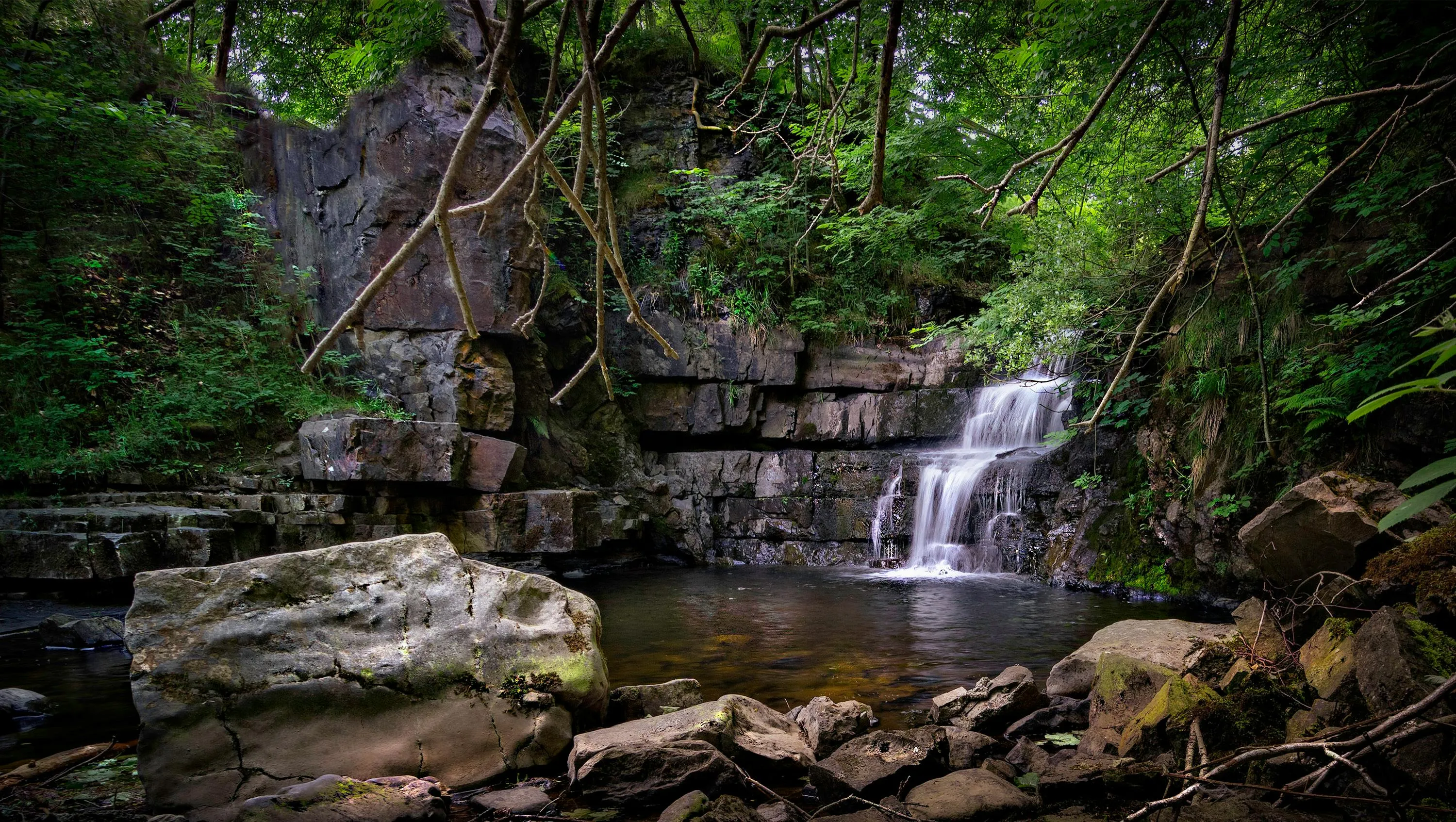 Small Waterfall Flows Through Rocks in the Forest Wallpaper