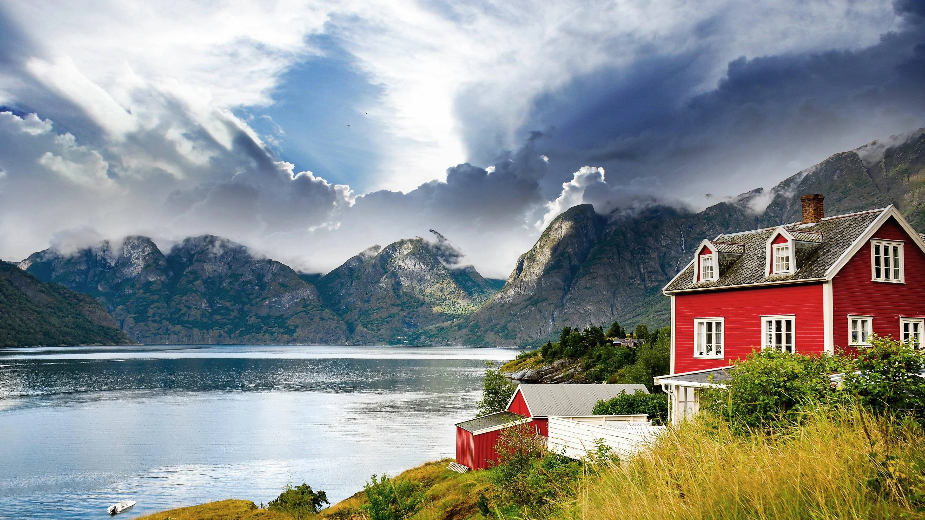 Snow capped mountains with a small red house by the lake