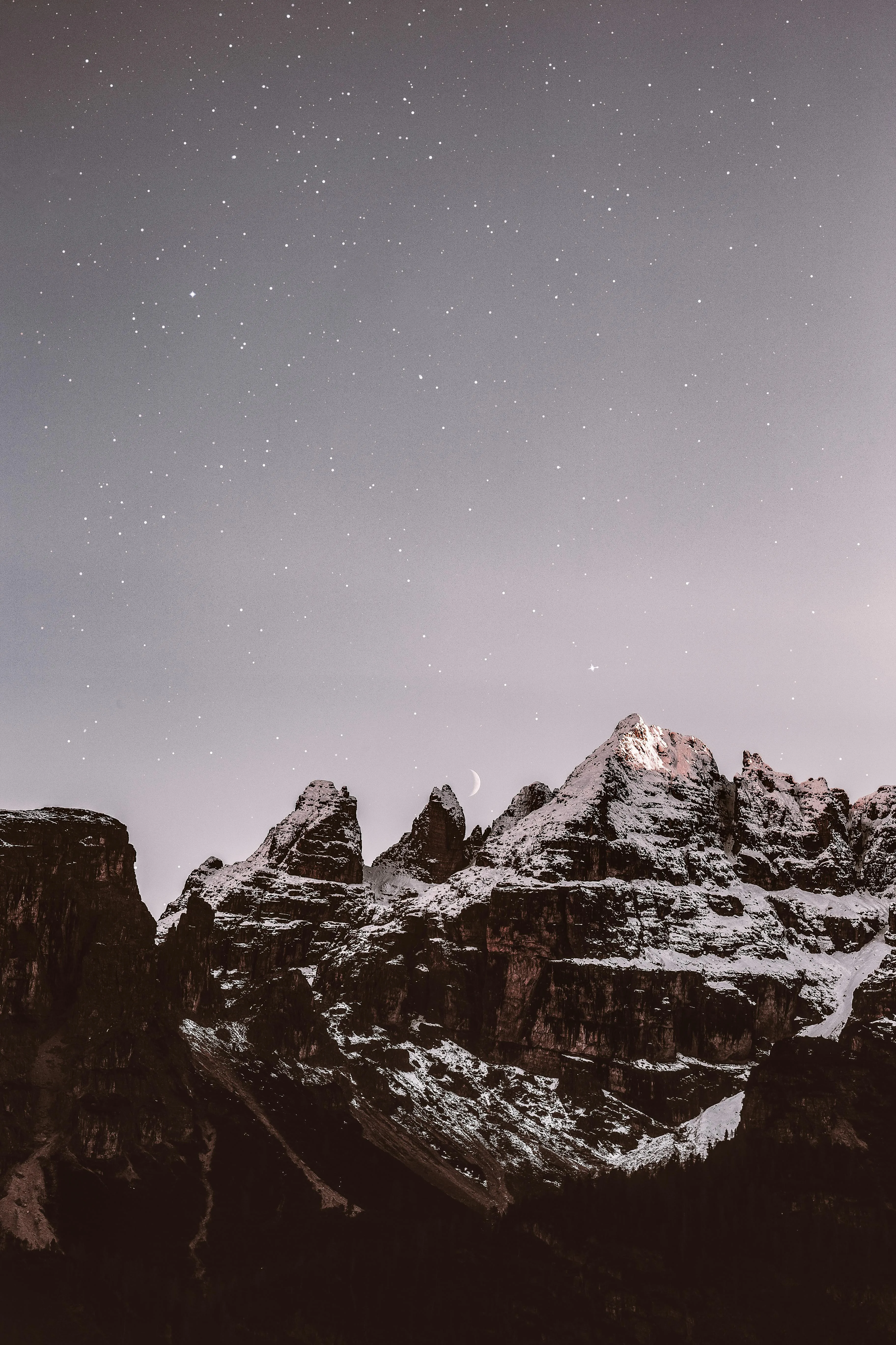 Snow Covered Mountain Peaks Under Starry Sky and Clouds