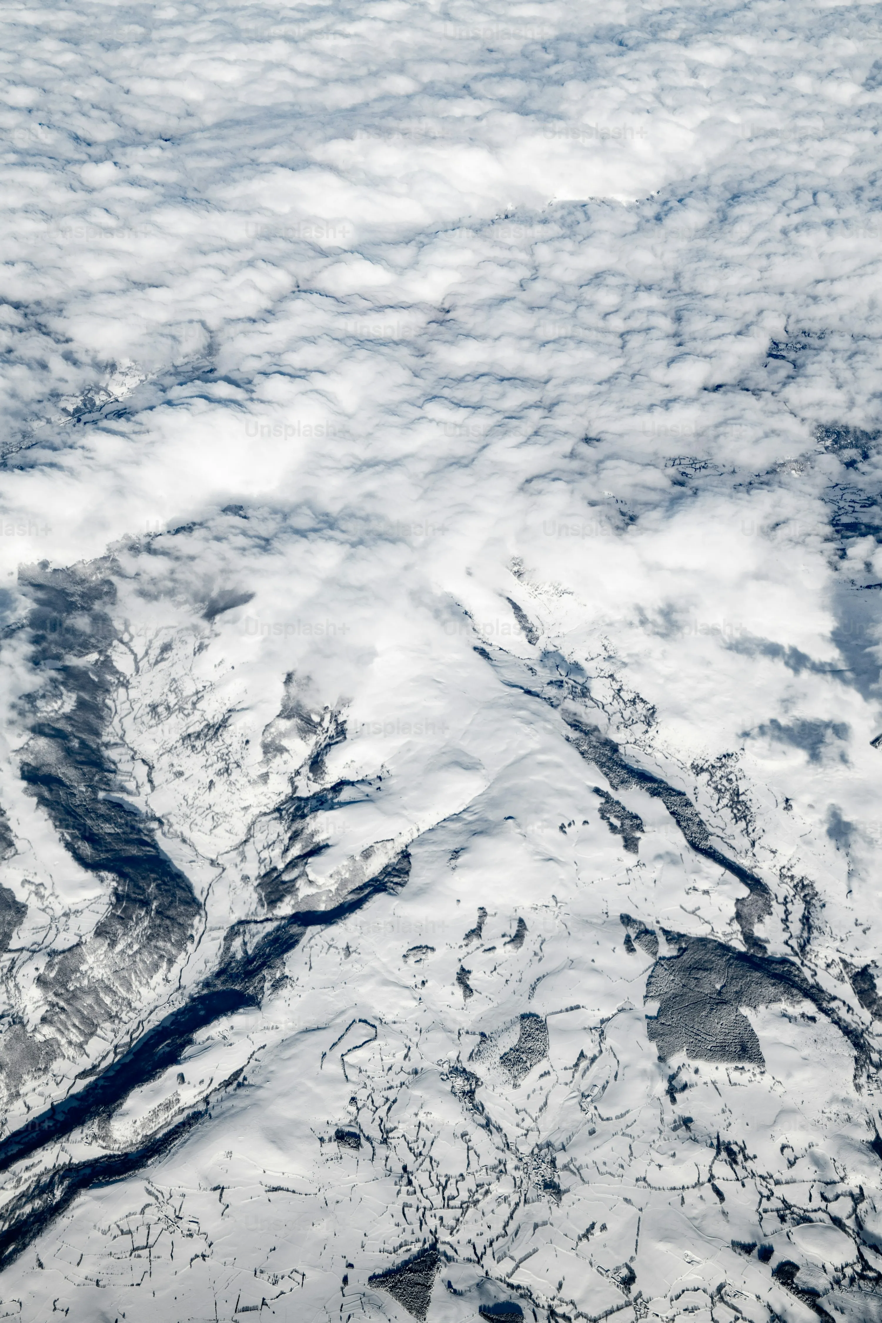 Snow Covered Mountains Seen From High Above with Clouds
