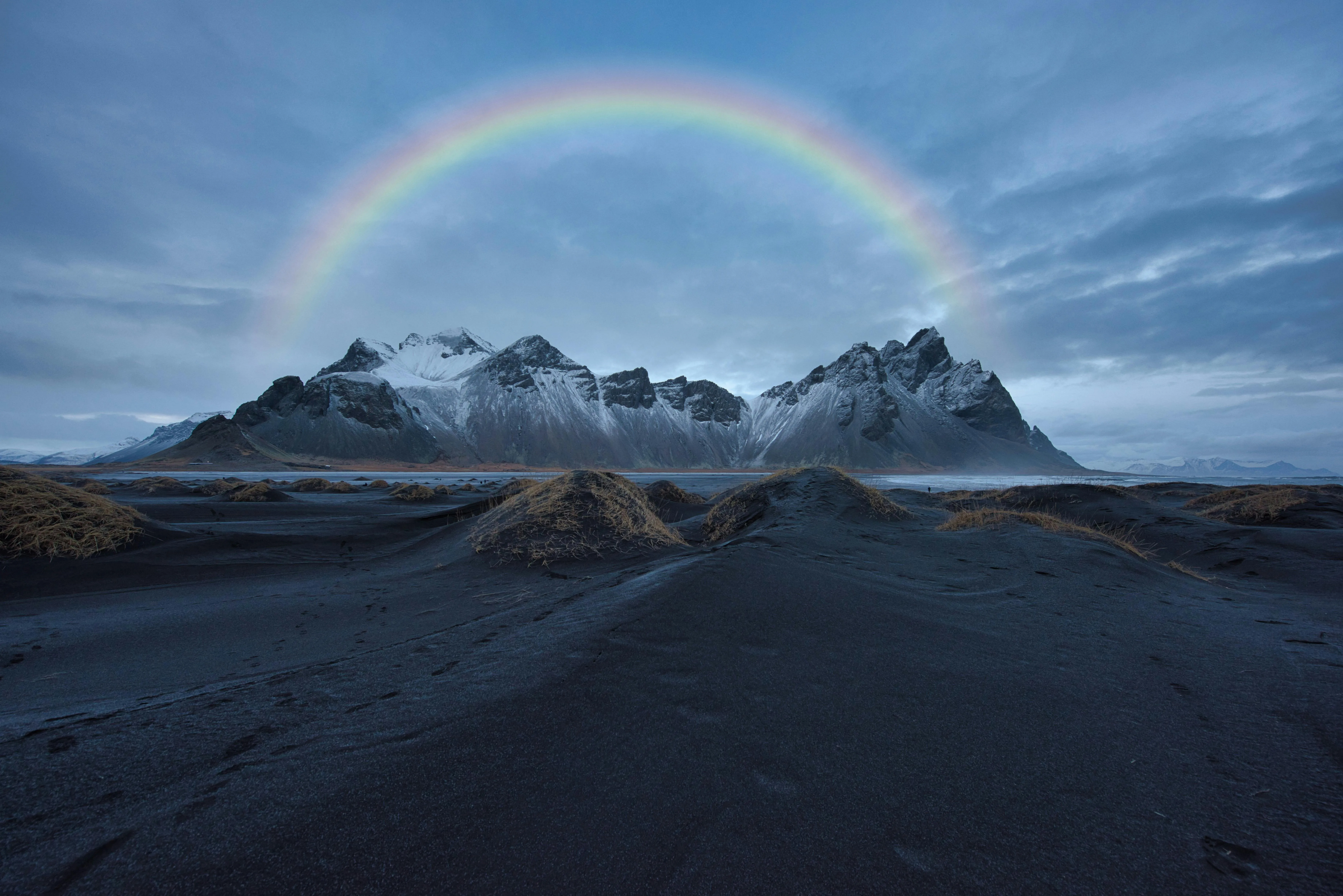 Snowy Mountain Landscape Under a Clear Blue Sky with Rainbow