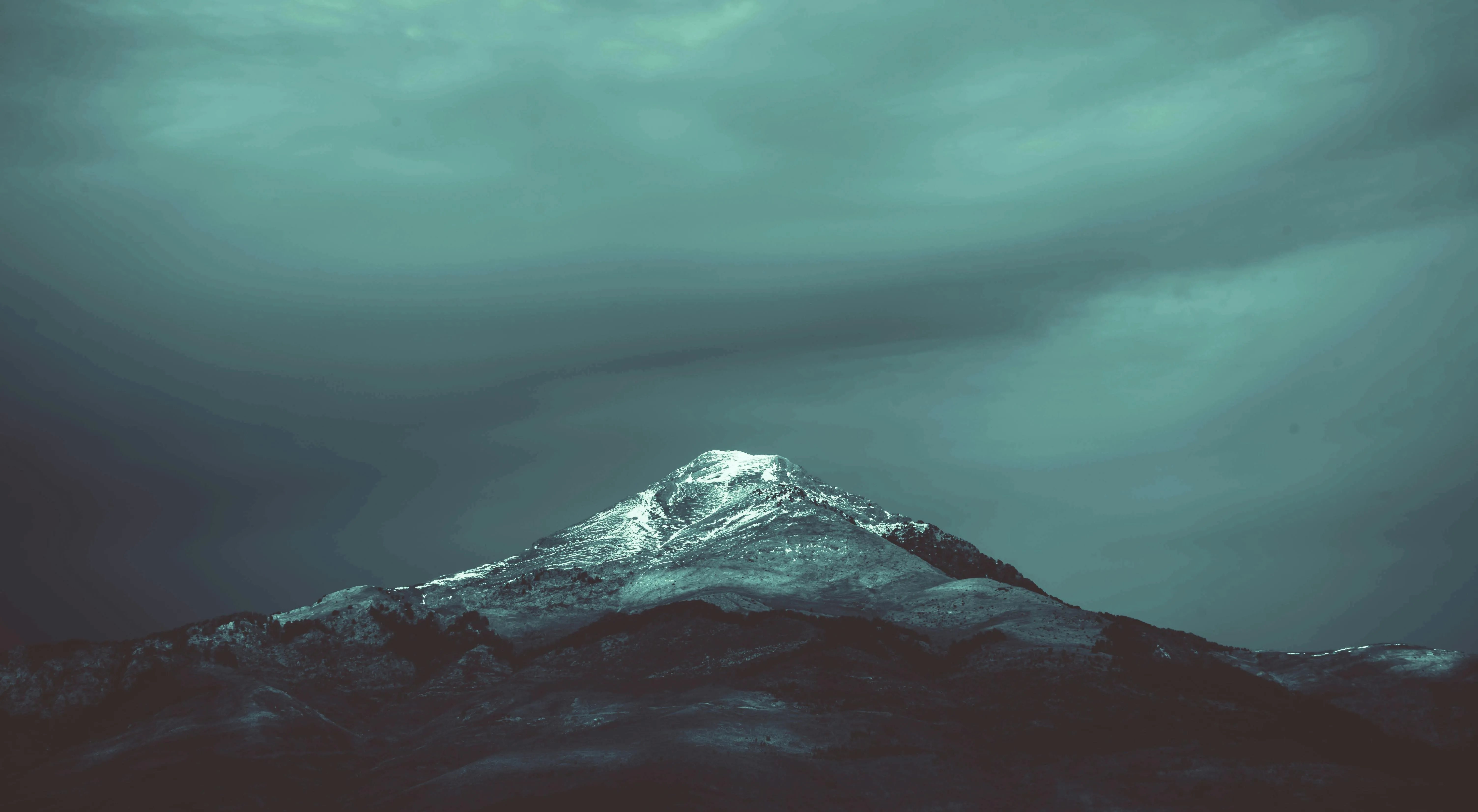 Snowy Mountain Peak Surrounded By Thick Clouds Wallpaper
