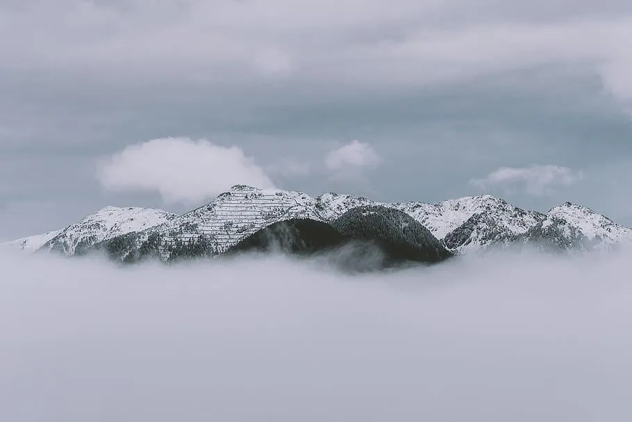 Snowy Mountain Peaks Peeking Through Low Cloud Fog Image