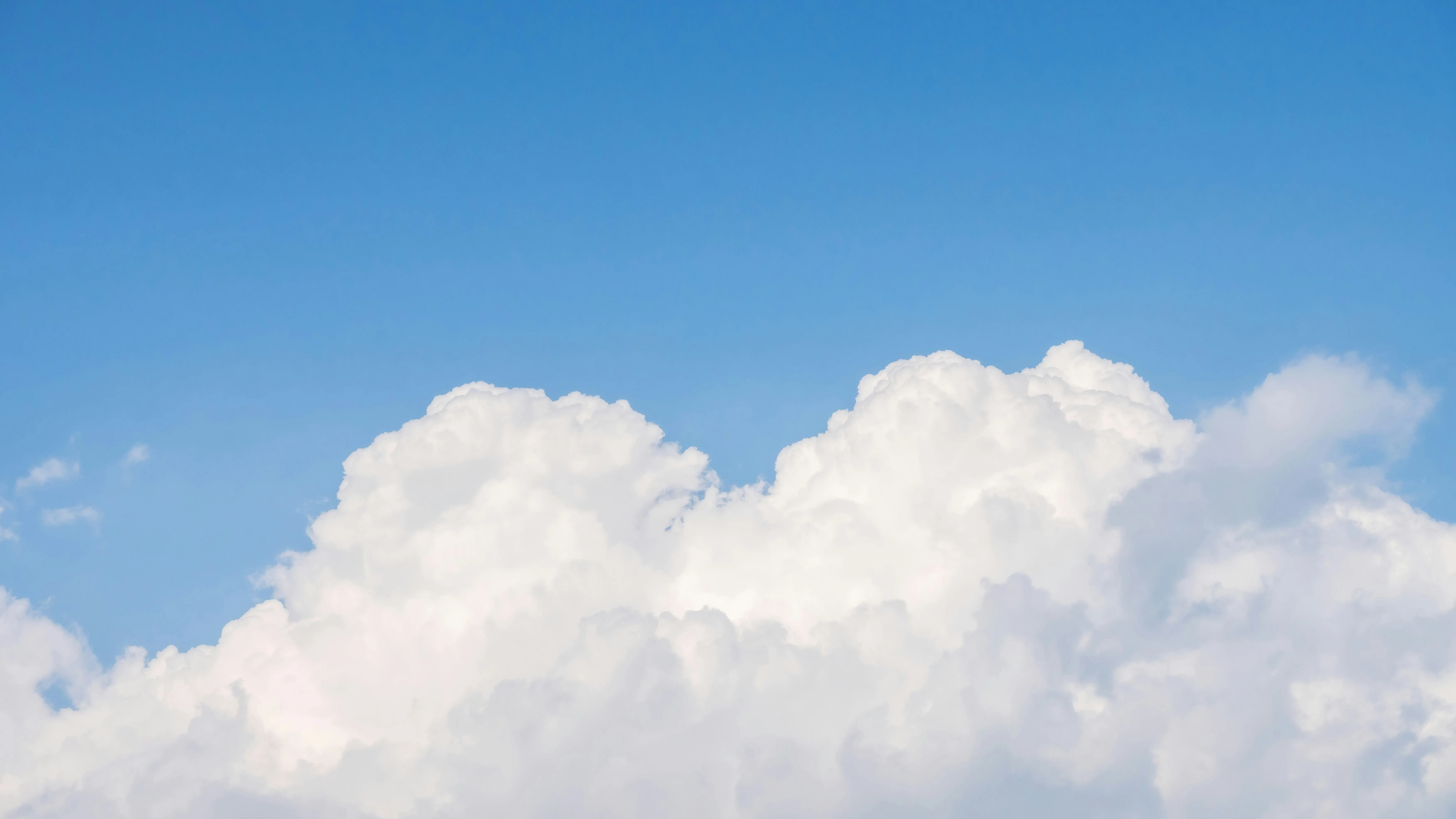 Soft Fluffy White Clouds Against a Pale Blue Sky Wallpaper