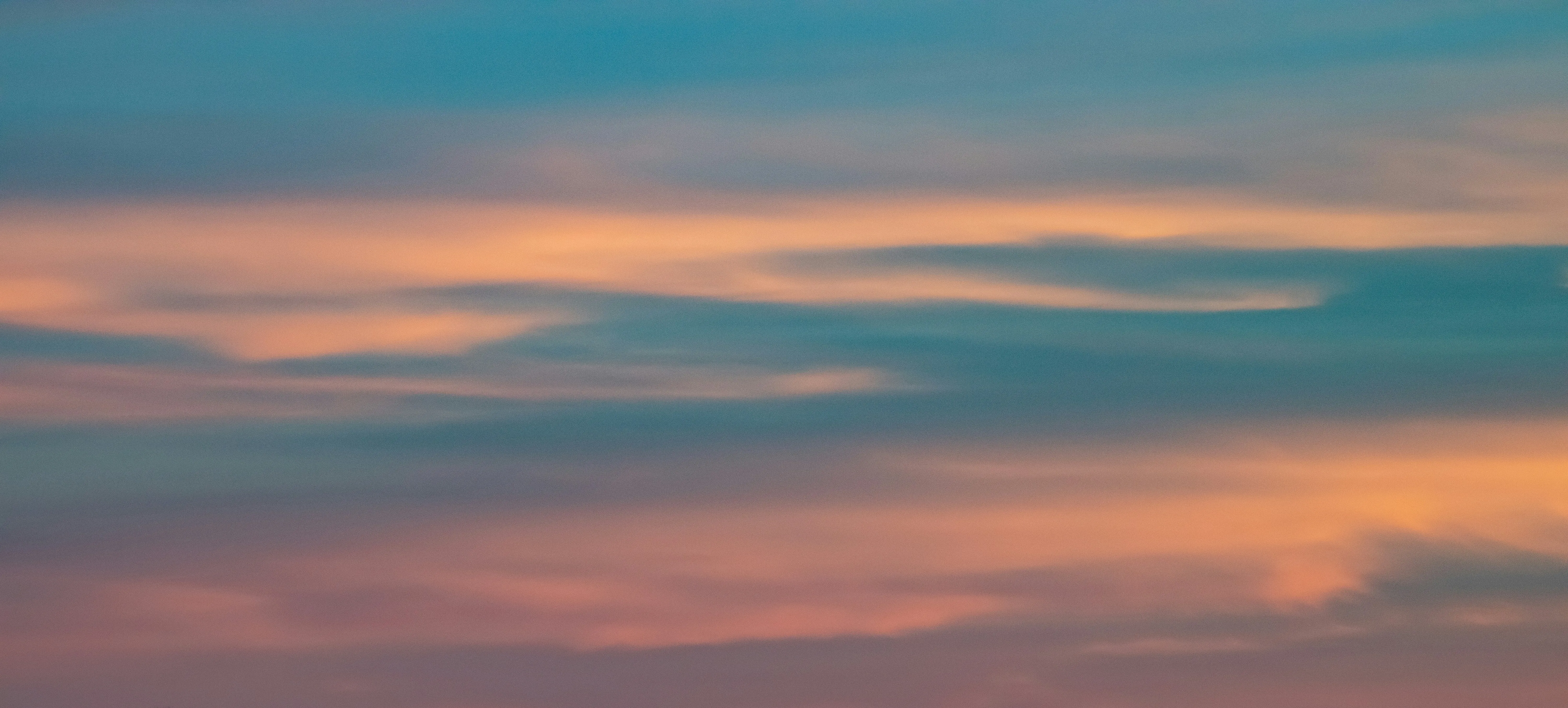 Soft Layered Clouds at Dusk in a Warm Toned Sky Wallpaper