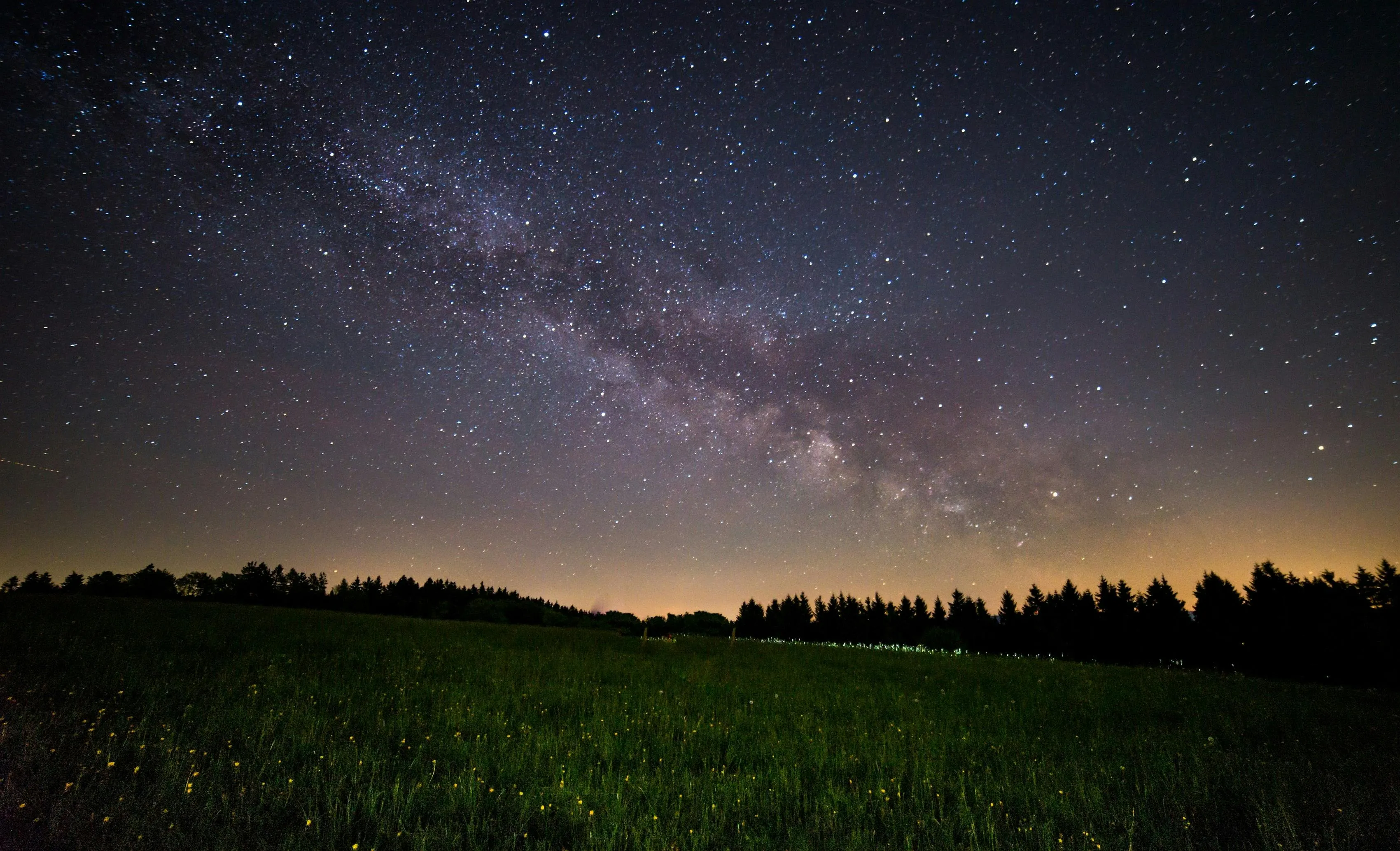 Starry Night Over Grassy Hill with Faint Cloud Layers Image
