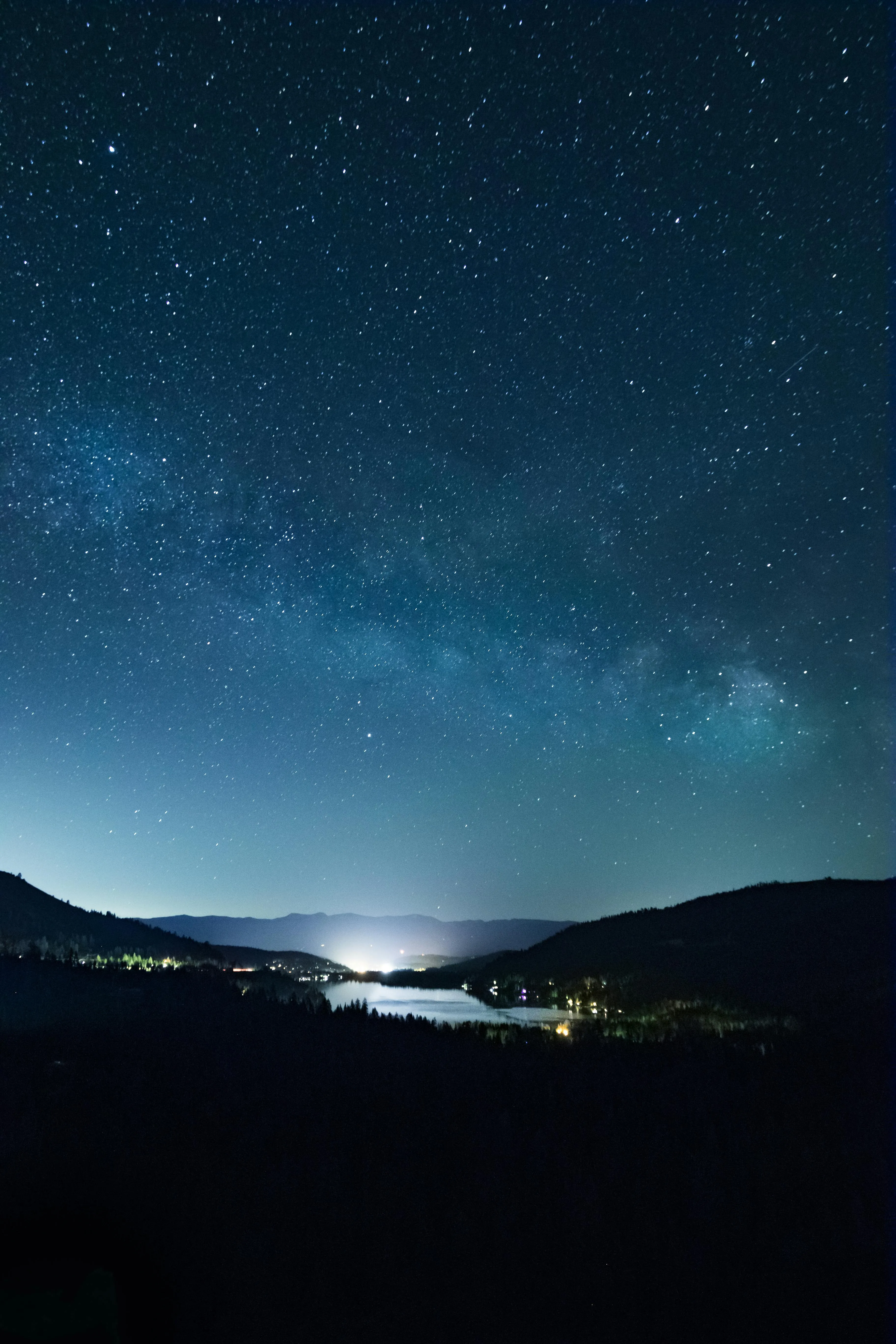 Starry Night Sky Over Mountain Landscape with City Lights