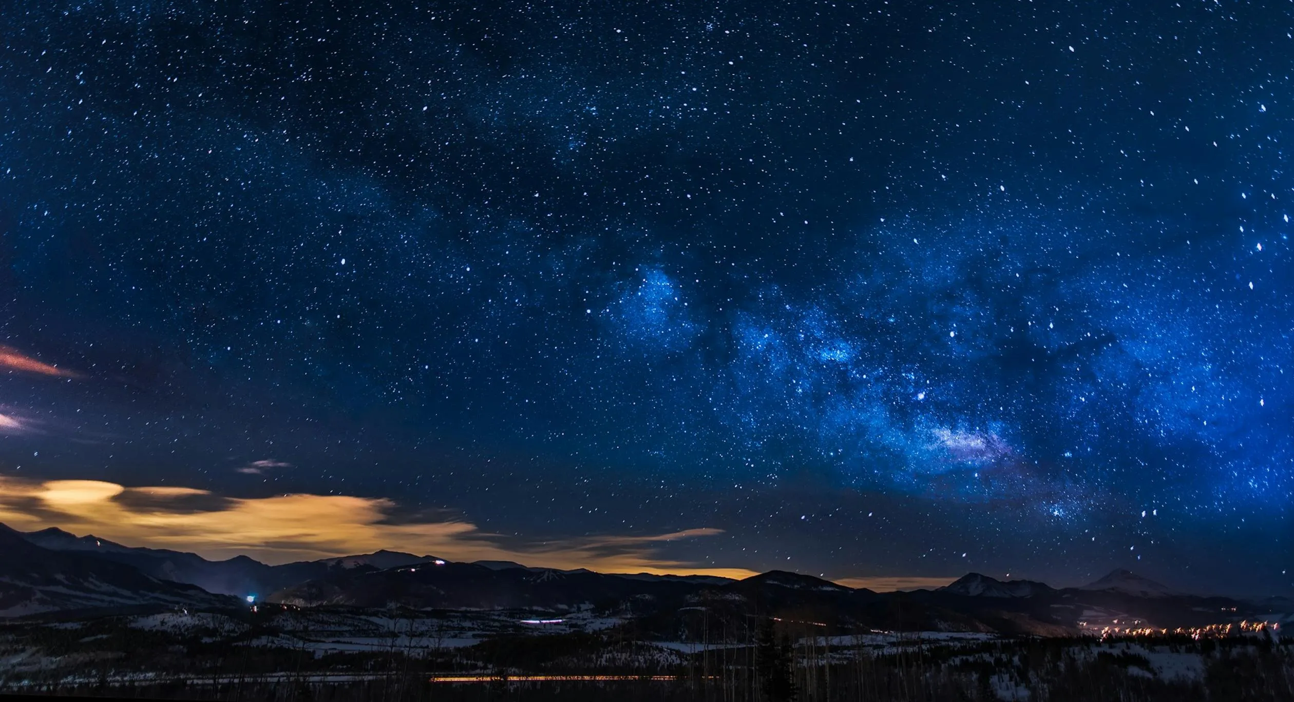 Starry Night Sky with Faint Clouds Over Mountains Wallpaper