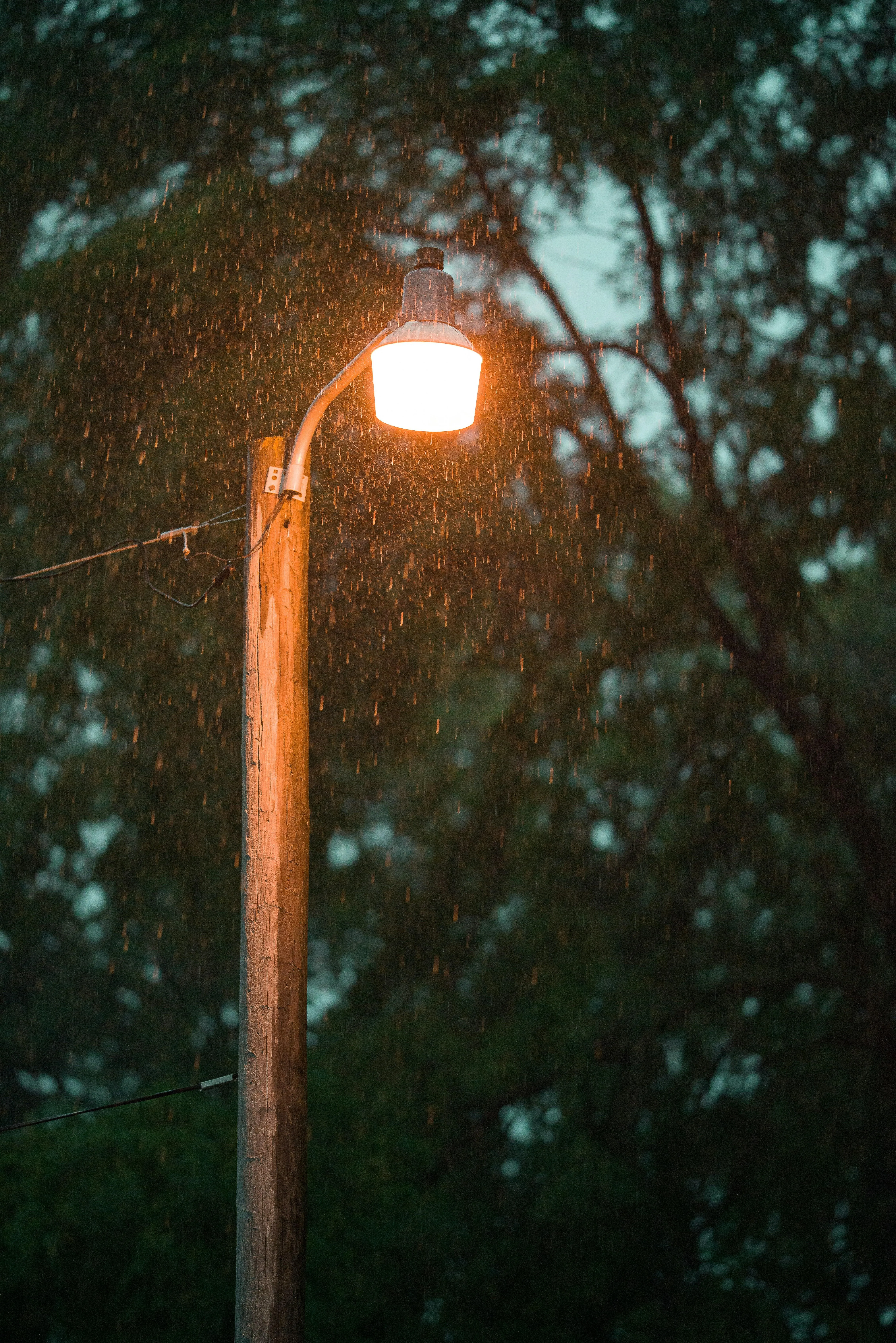 Street Lamp Glowing Warmly in Rainy Urban Street Wallpaper