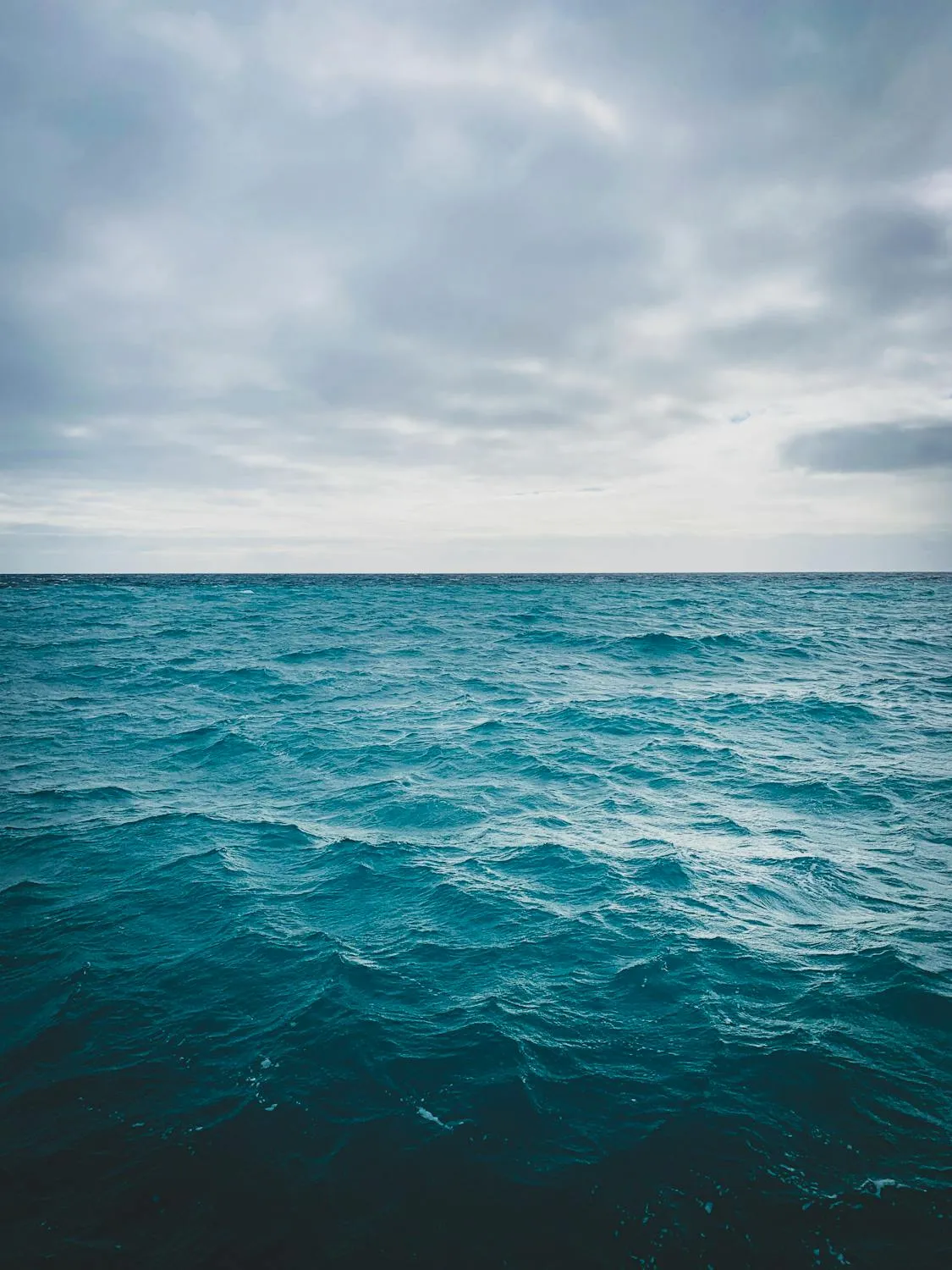 Stunning Calm Ocean Under Gray Cloudy Sky with Horizon