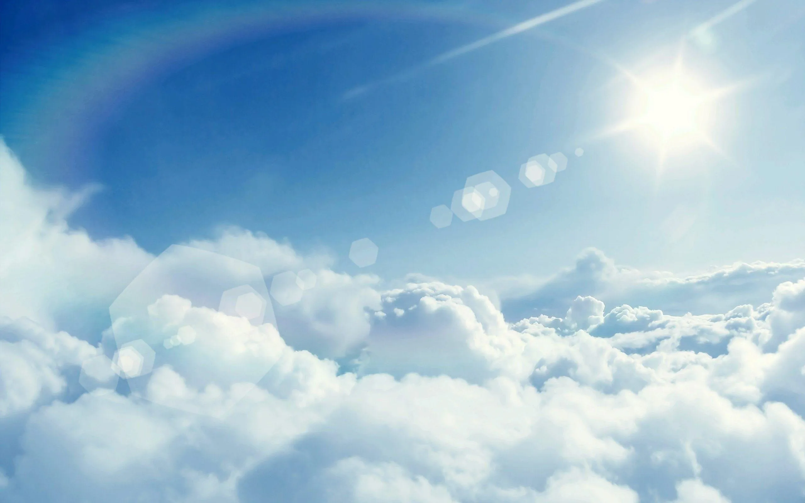 Sun Shining Over Blue Clouds with a Rainbow Wallpaper