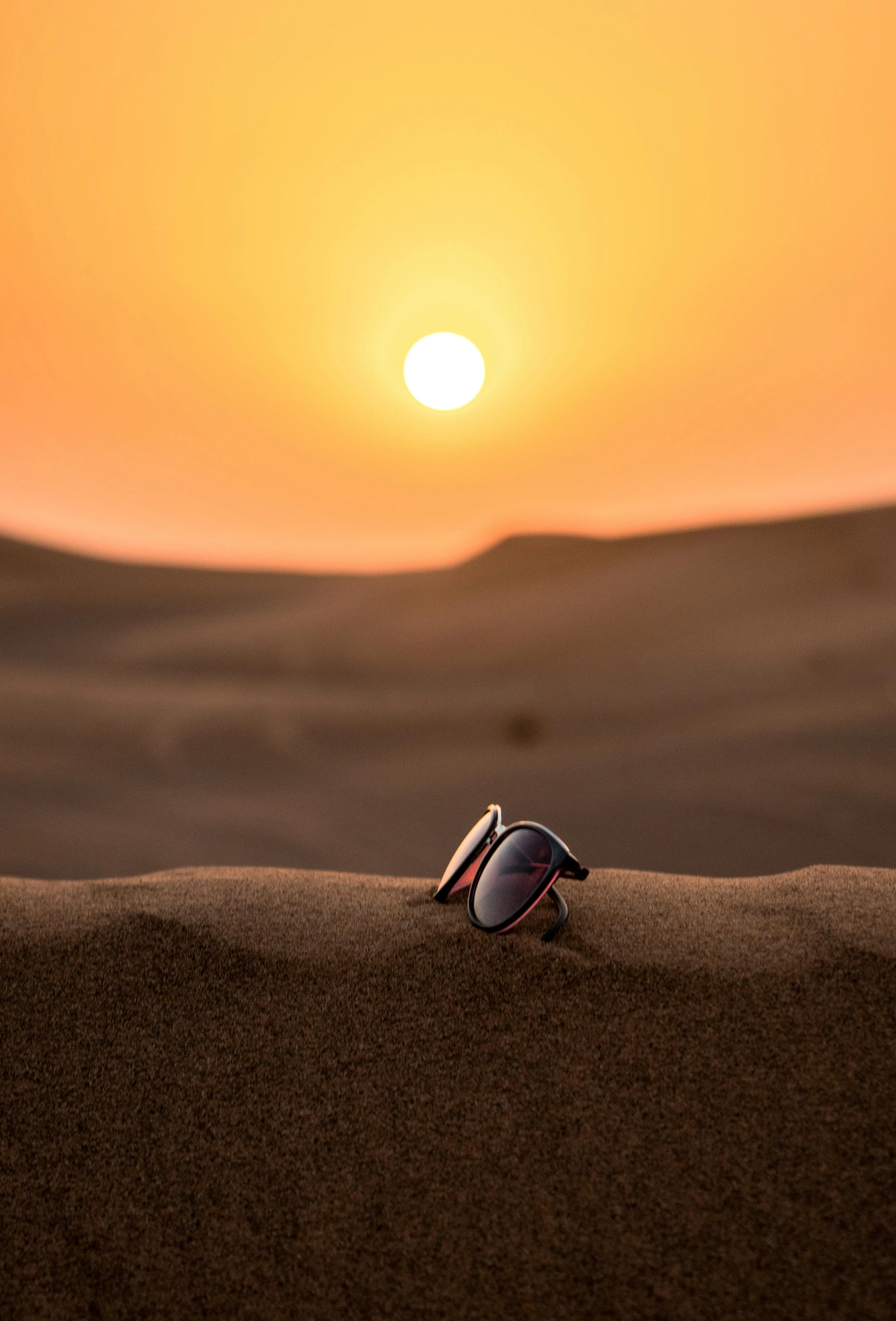 Sunglasses Placed Alone in Desert with Bright Sun Setting