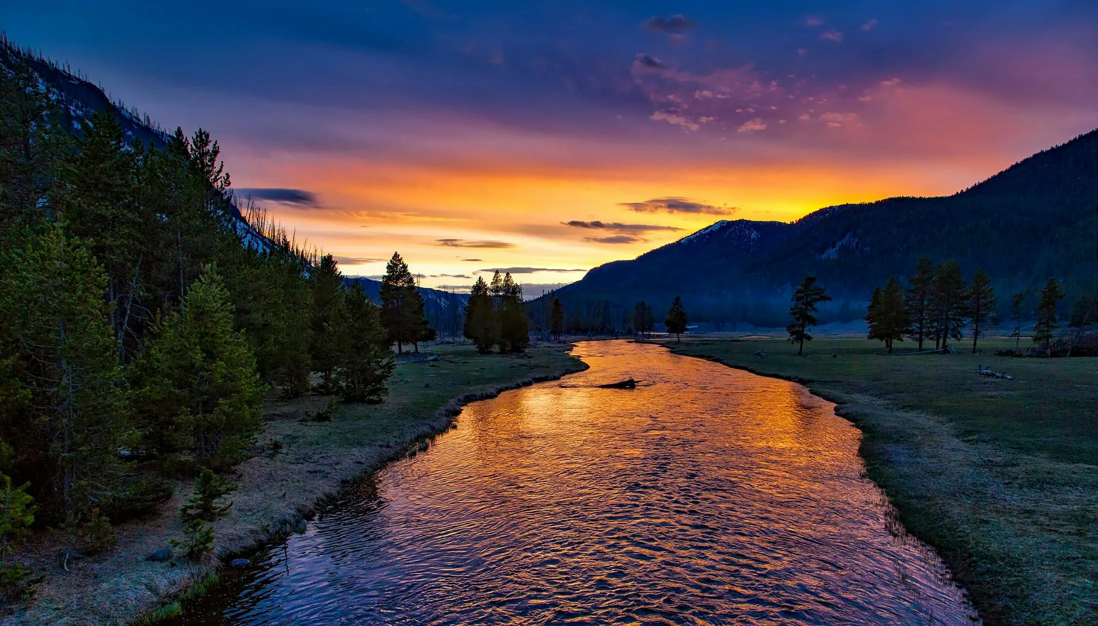 Sunset Over a Calm River with Pine Trees and a Mountain Peak