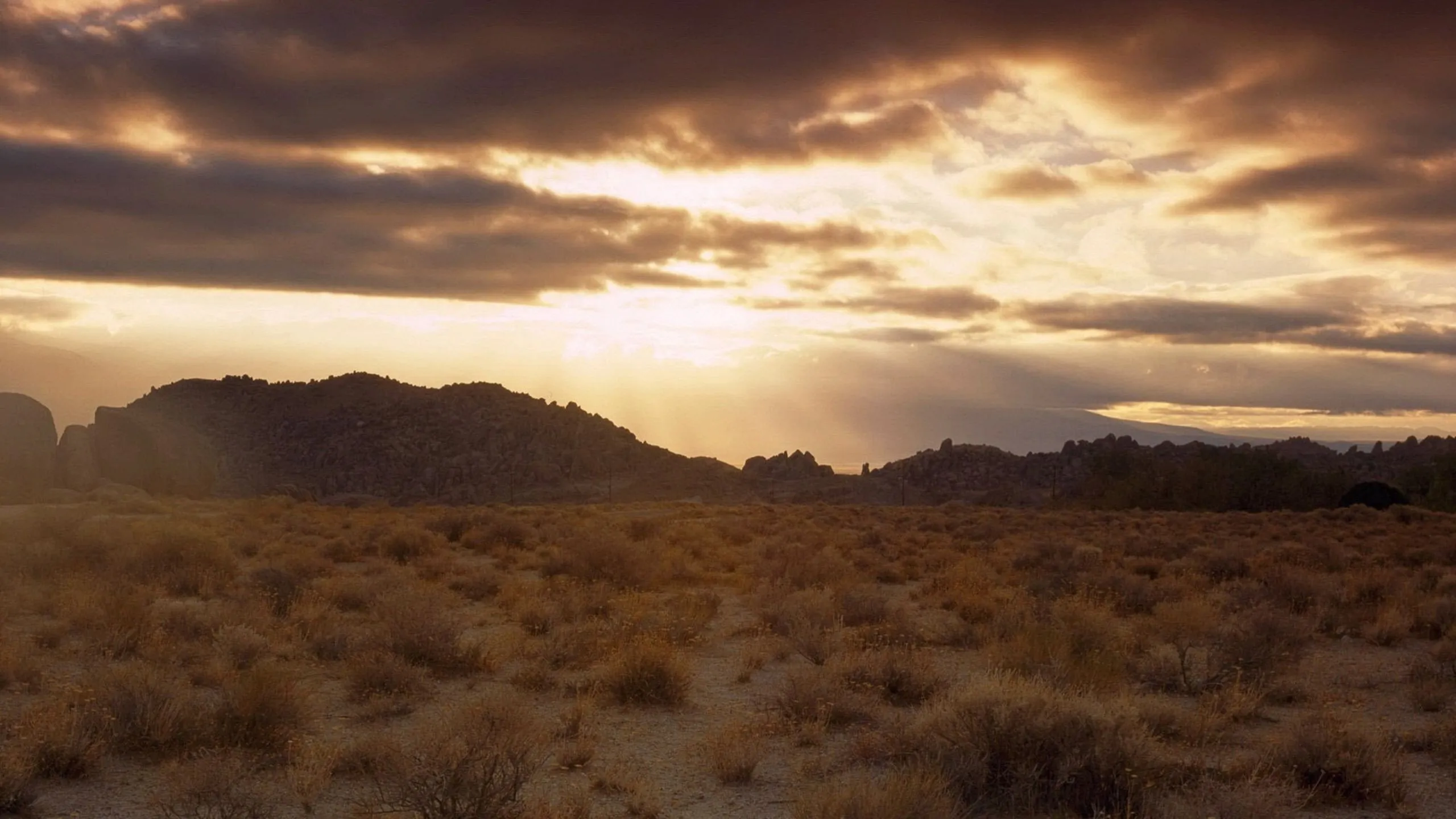Sunset Over Desert Landscape with Moody Cloudy Skies Image