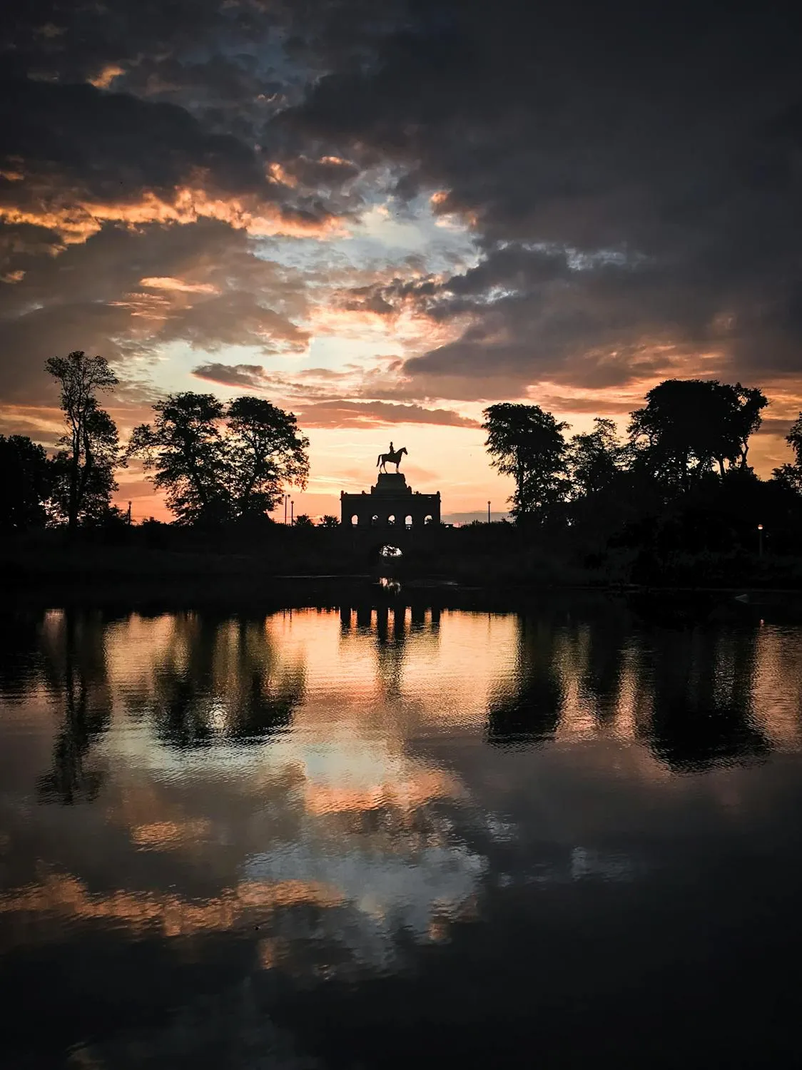 Sunset Over Lake with Silhouetted Trees and Statue Image