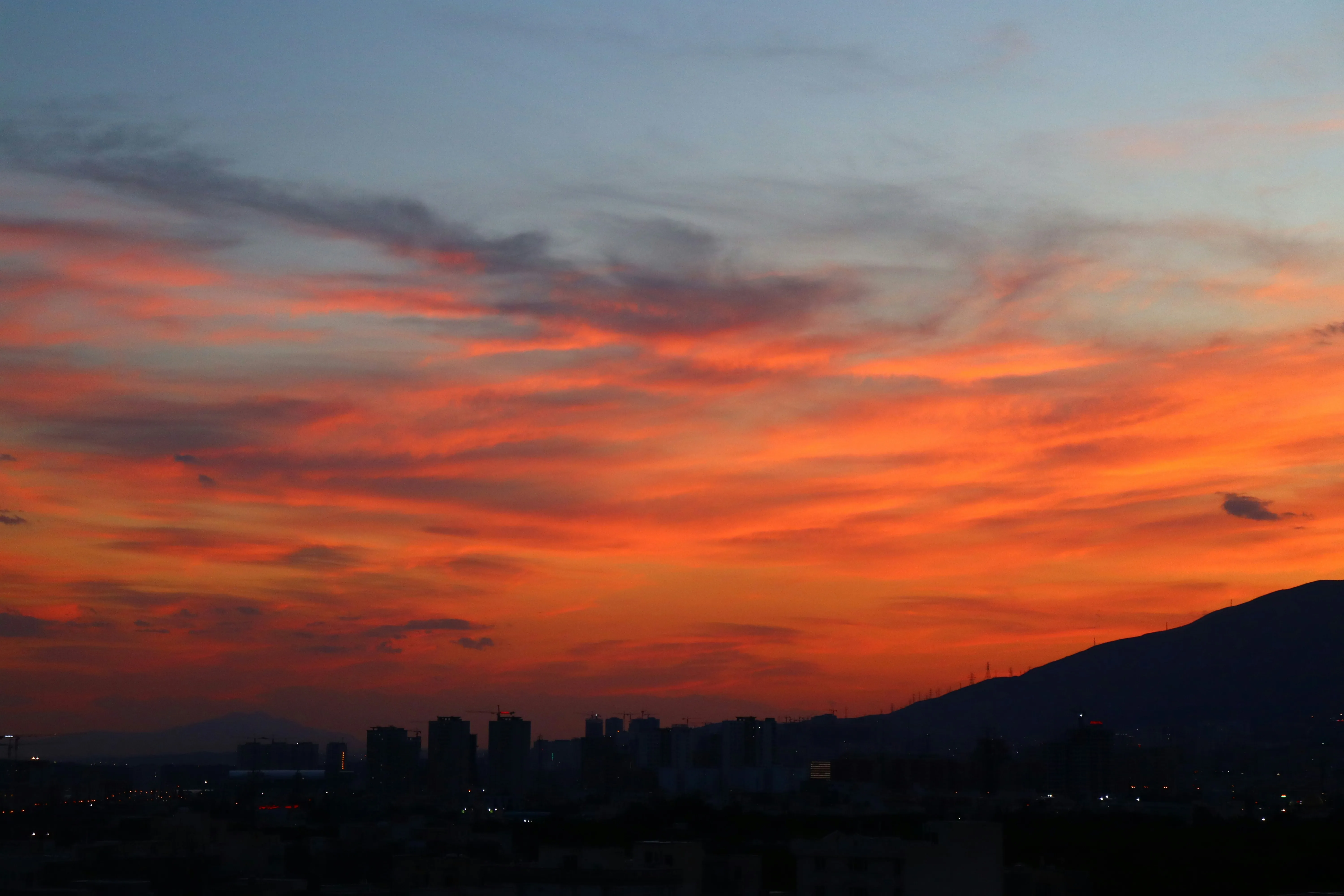 Sunset Sky Over City with Dark Silhouettes and Orange Clouds
