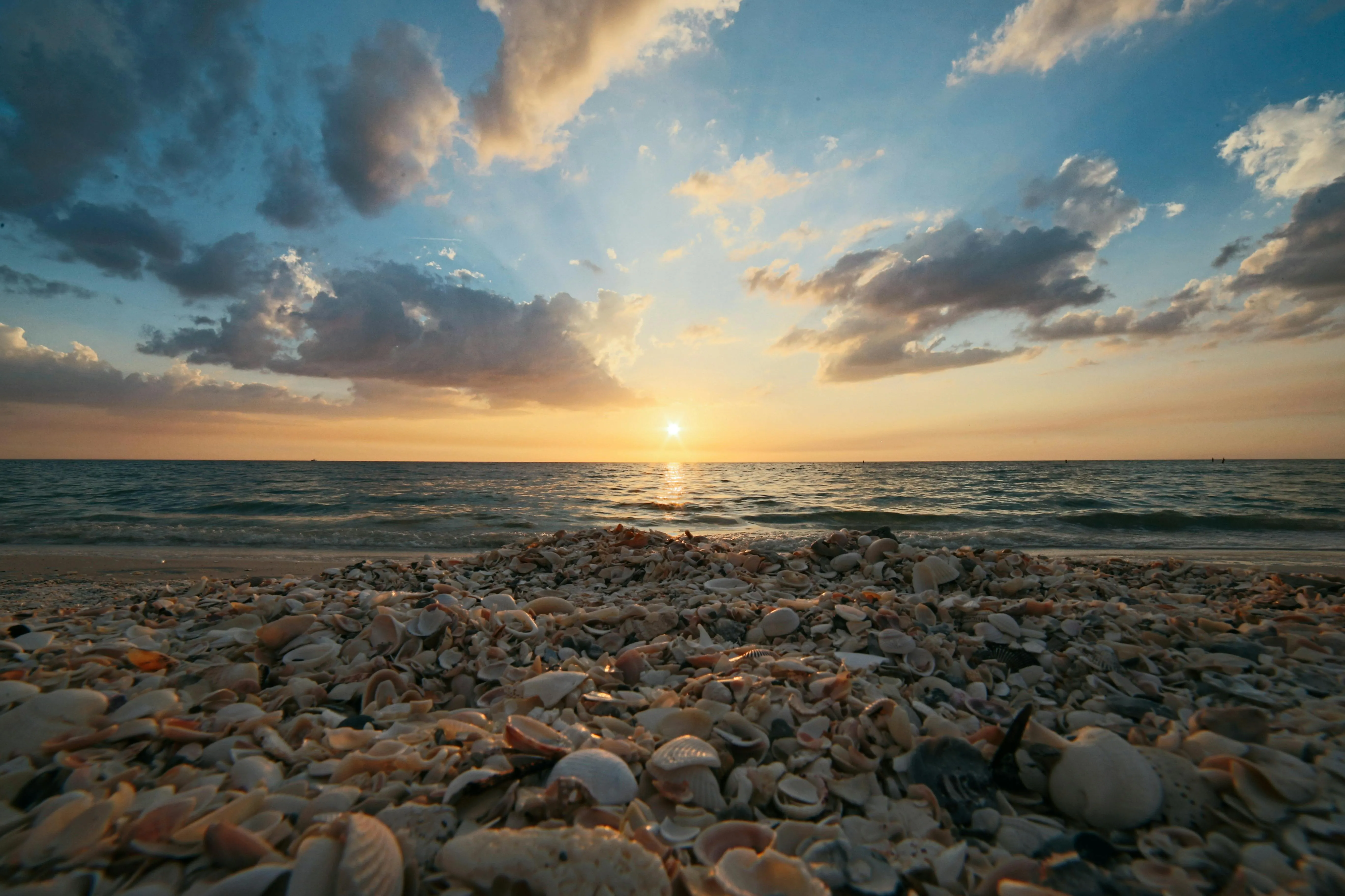 Sunset Sky with Glowing Clouds Over a Rocky Beach Wallpaper