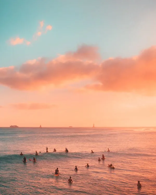 Surfers Enjoying Ocean Waves at Sunset with Pink Sky