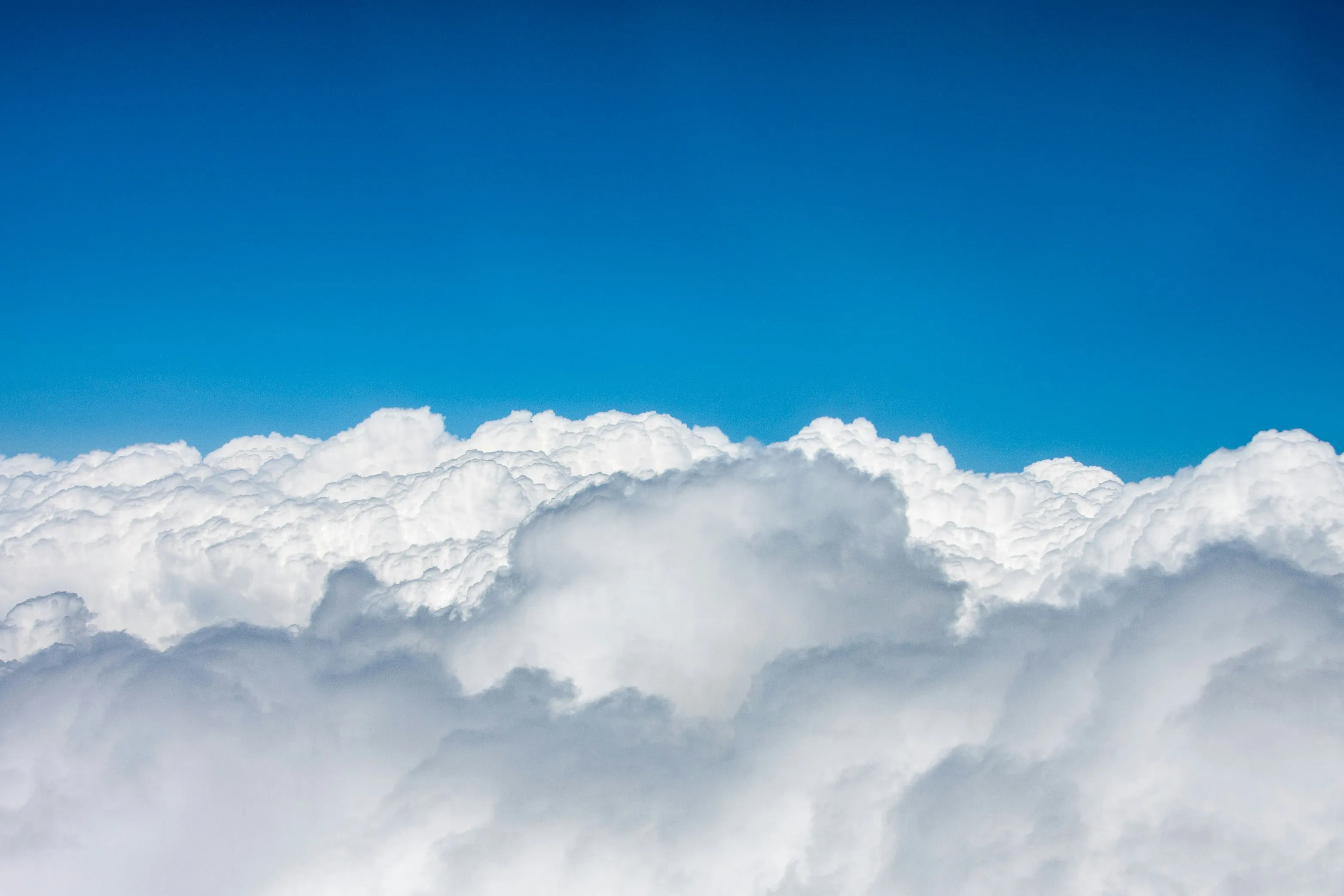 Thick White Clouds Stretching Into Deep Blue Sky Wallpaper