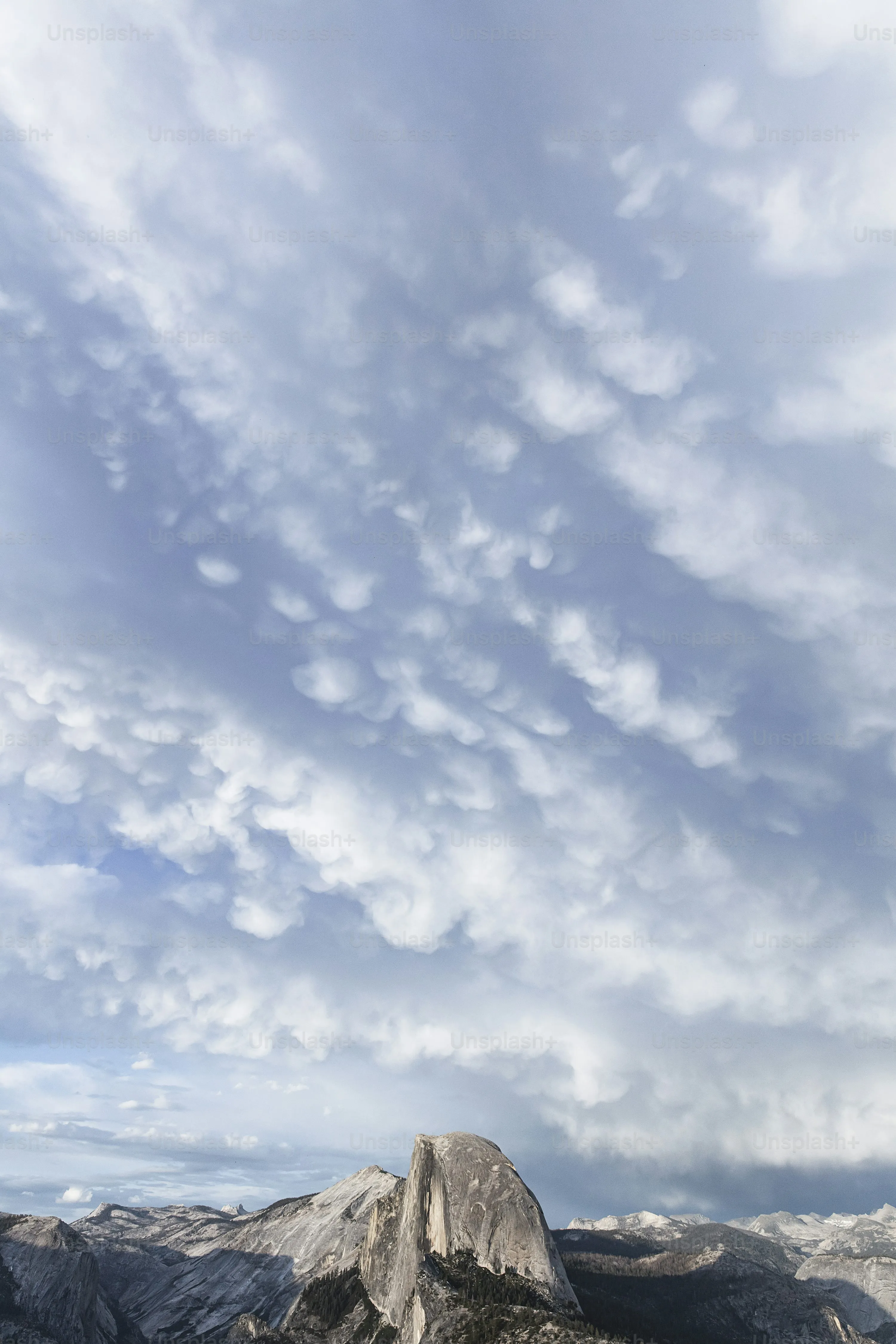 Towering Clouds Above Mountain with Deep Blue Sky Image