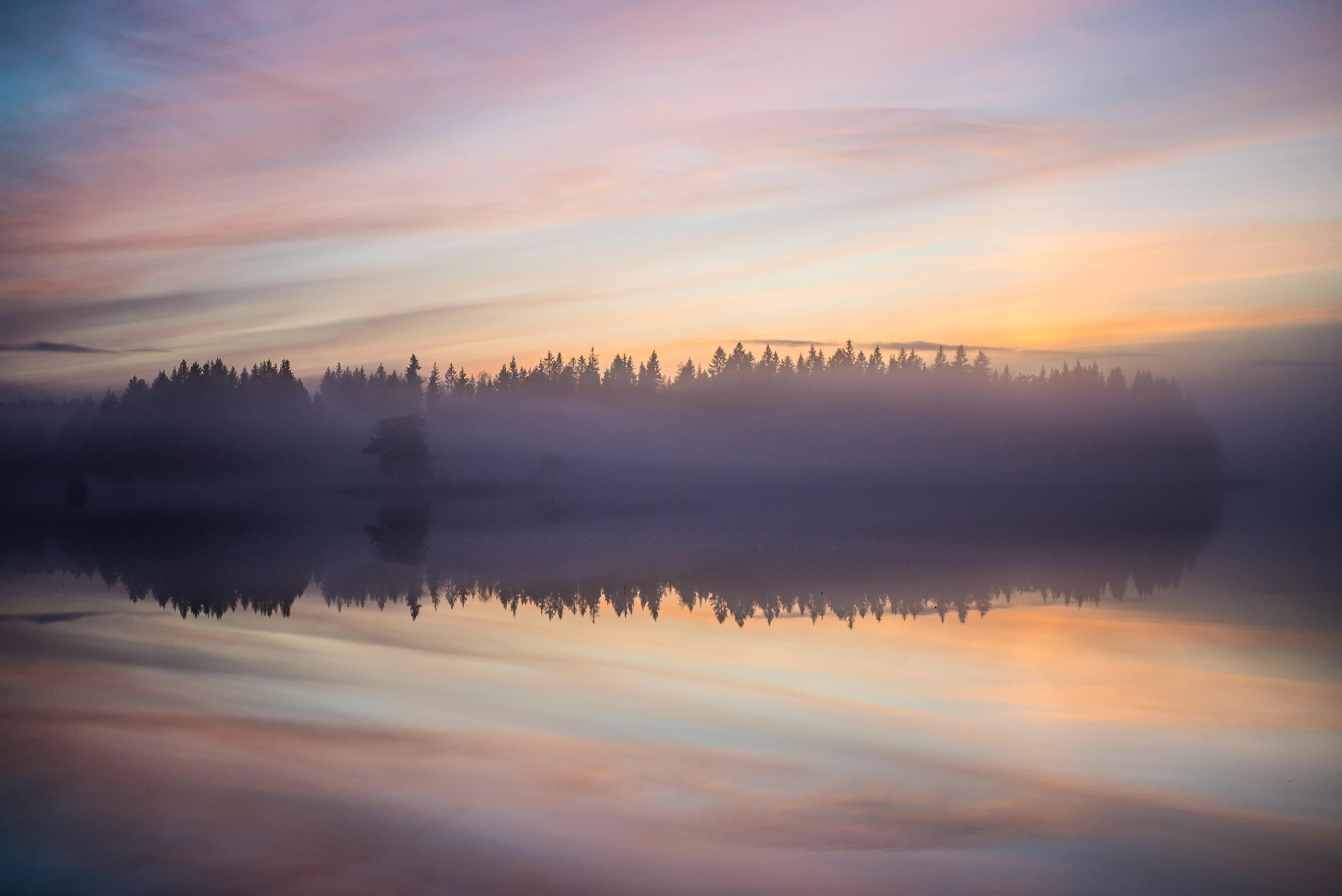 Tranquil lake at sunrise with misty reflections image