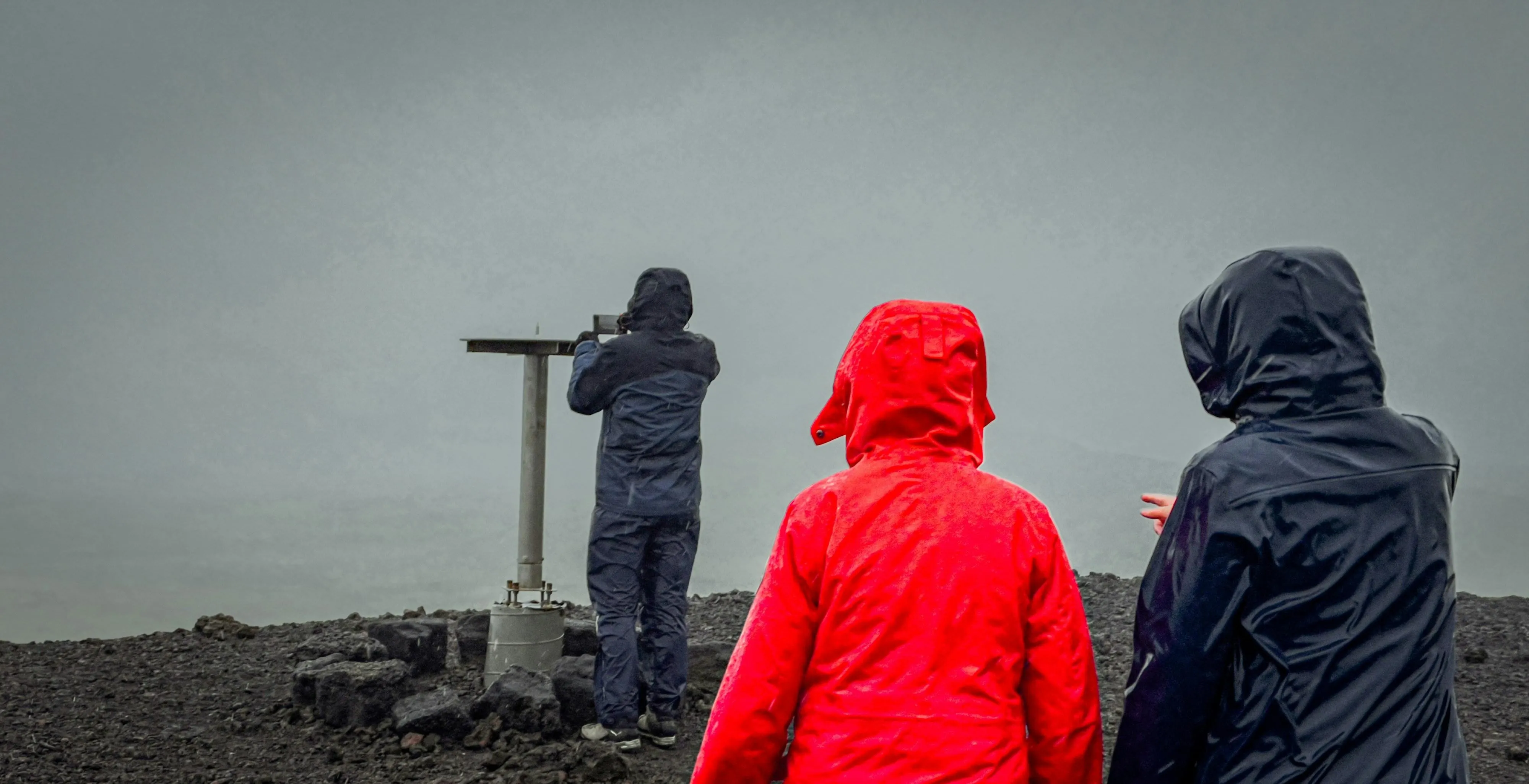 Two People with Hooded Jackets Standing Near Foggy Coast