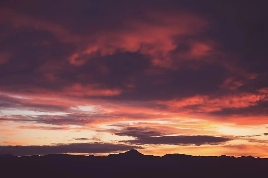 Vibrant Red and Purple Sunset Sky Over Mountain Range