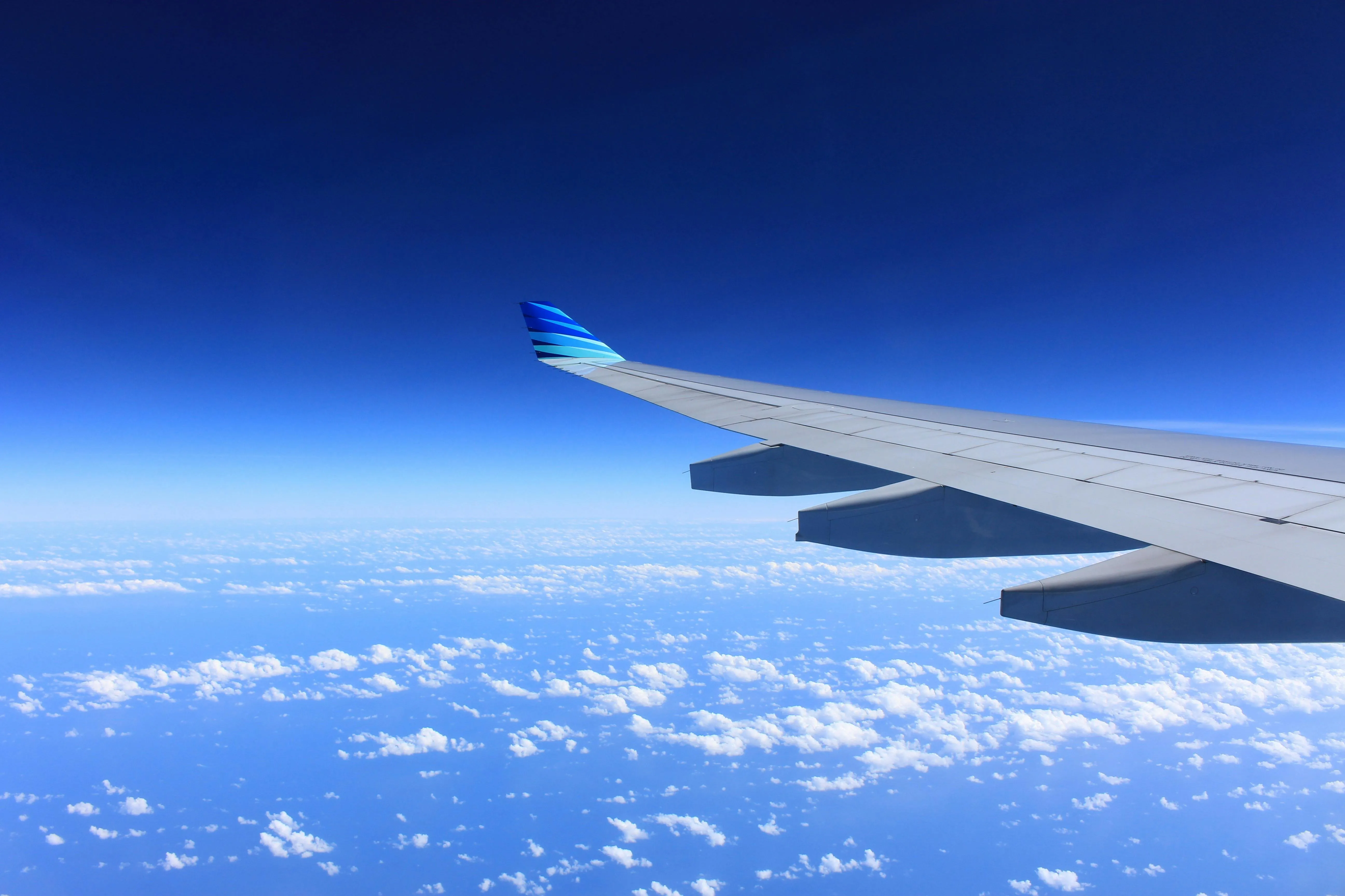 View of Airplane Wing Over Blue Sky with Scattered Clouds