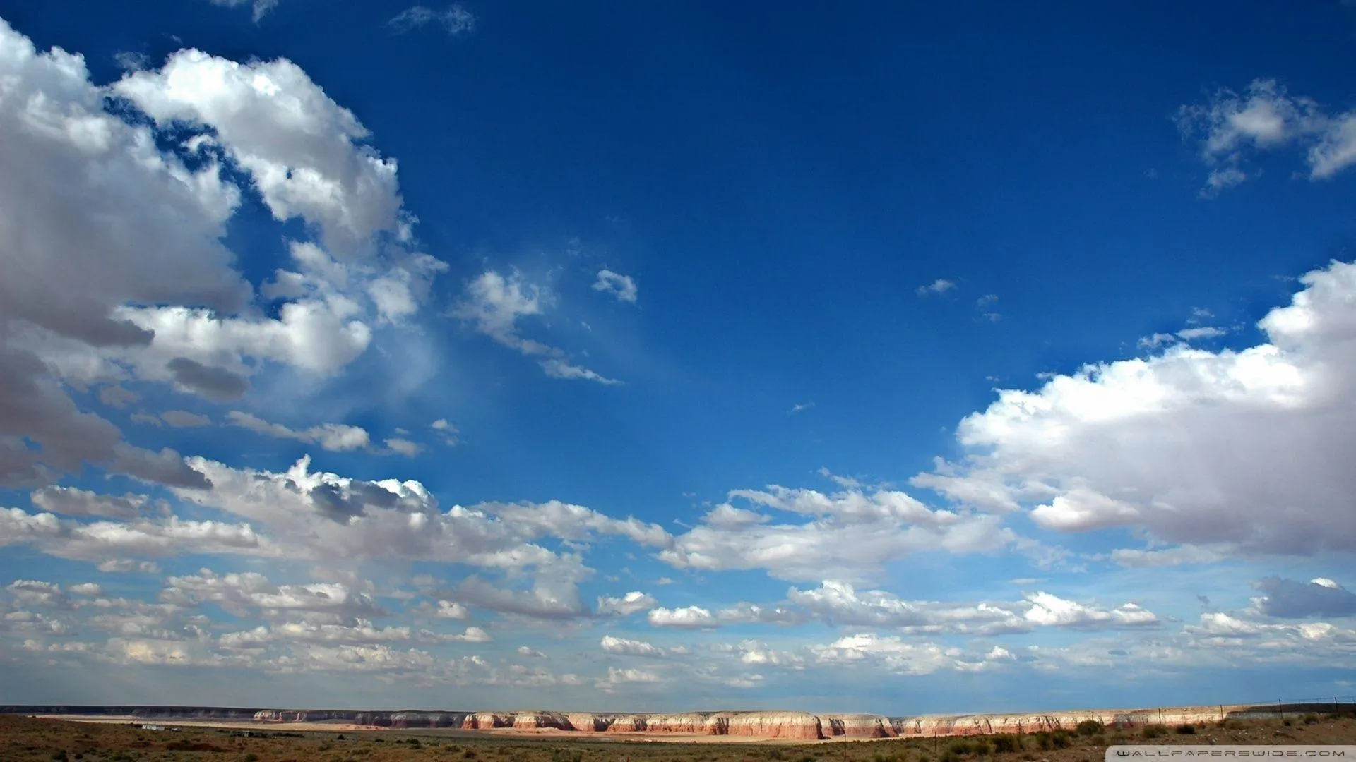 Vivid Blue Sky with Large Fluffy Clouds Over Open Landscape
