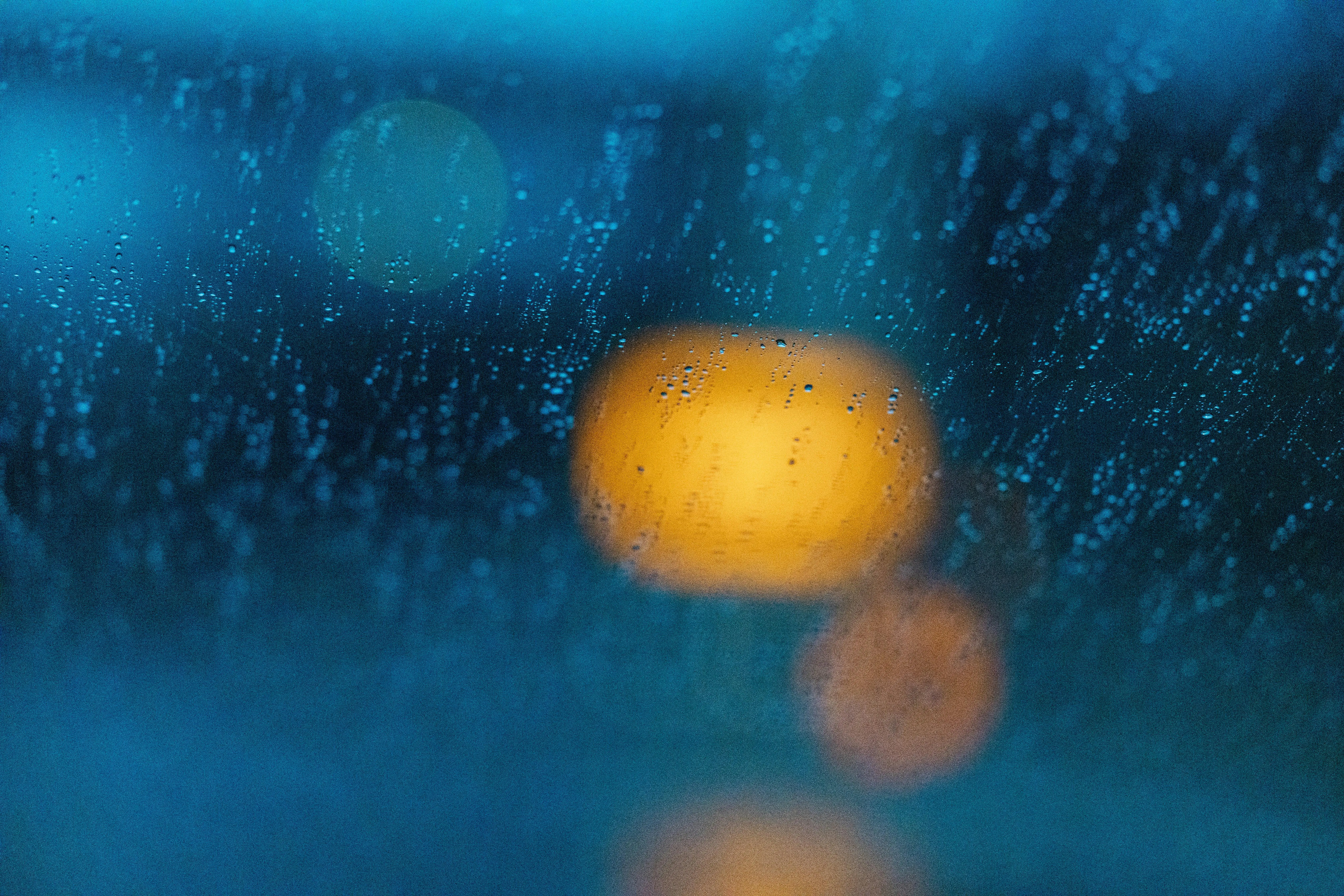 Wallpaper of Blurred Streetlight Glowing Through Rainy Window