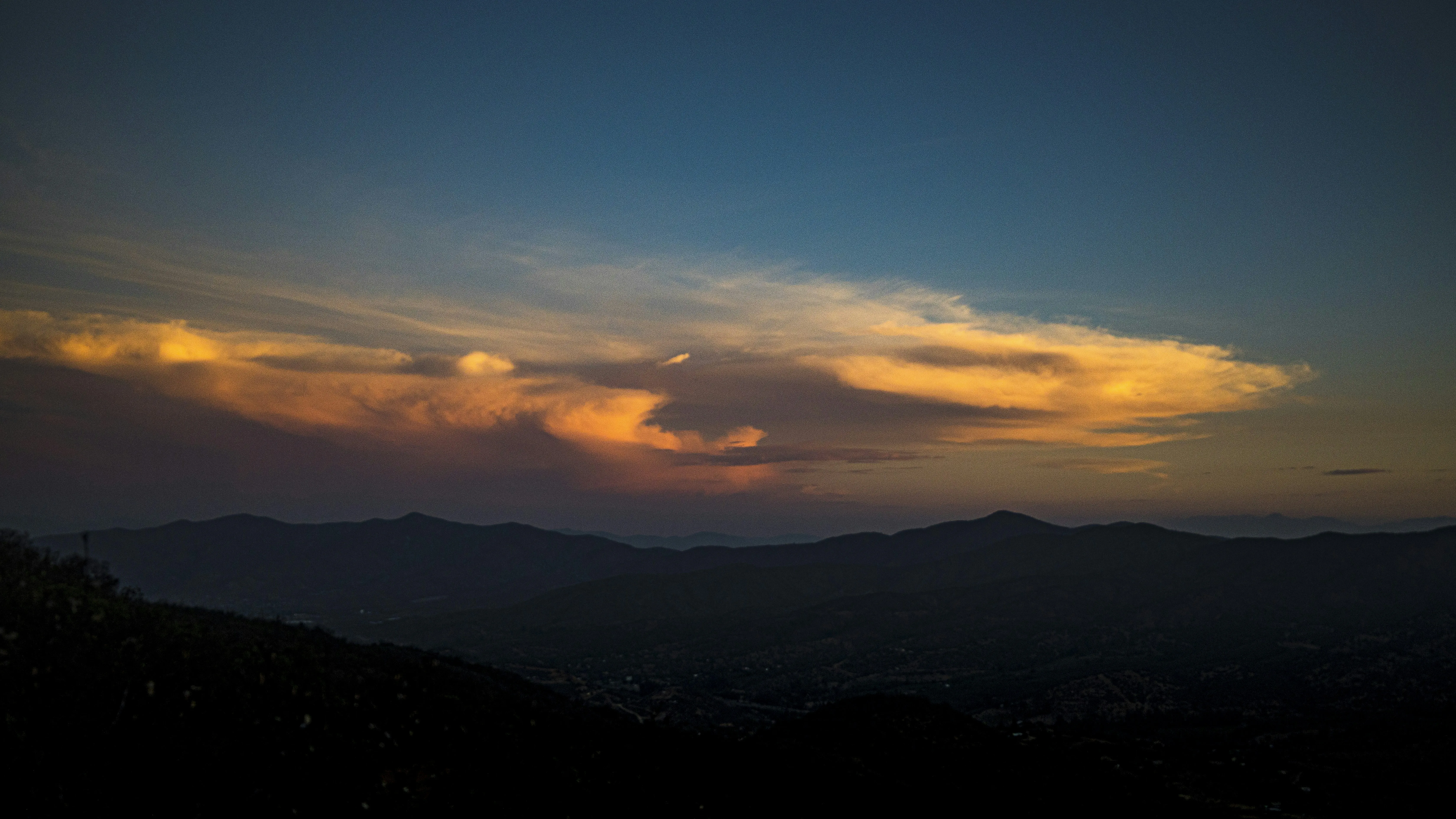 Warm Sunset Over Hills with Low Clouds and Fading Light