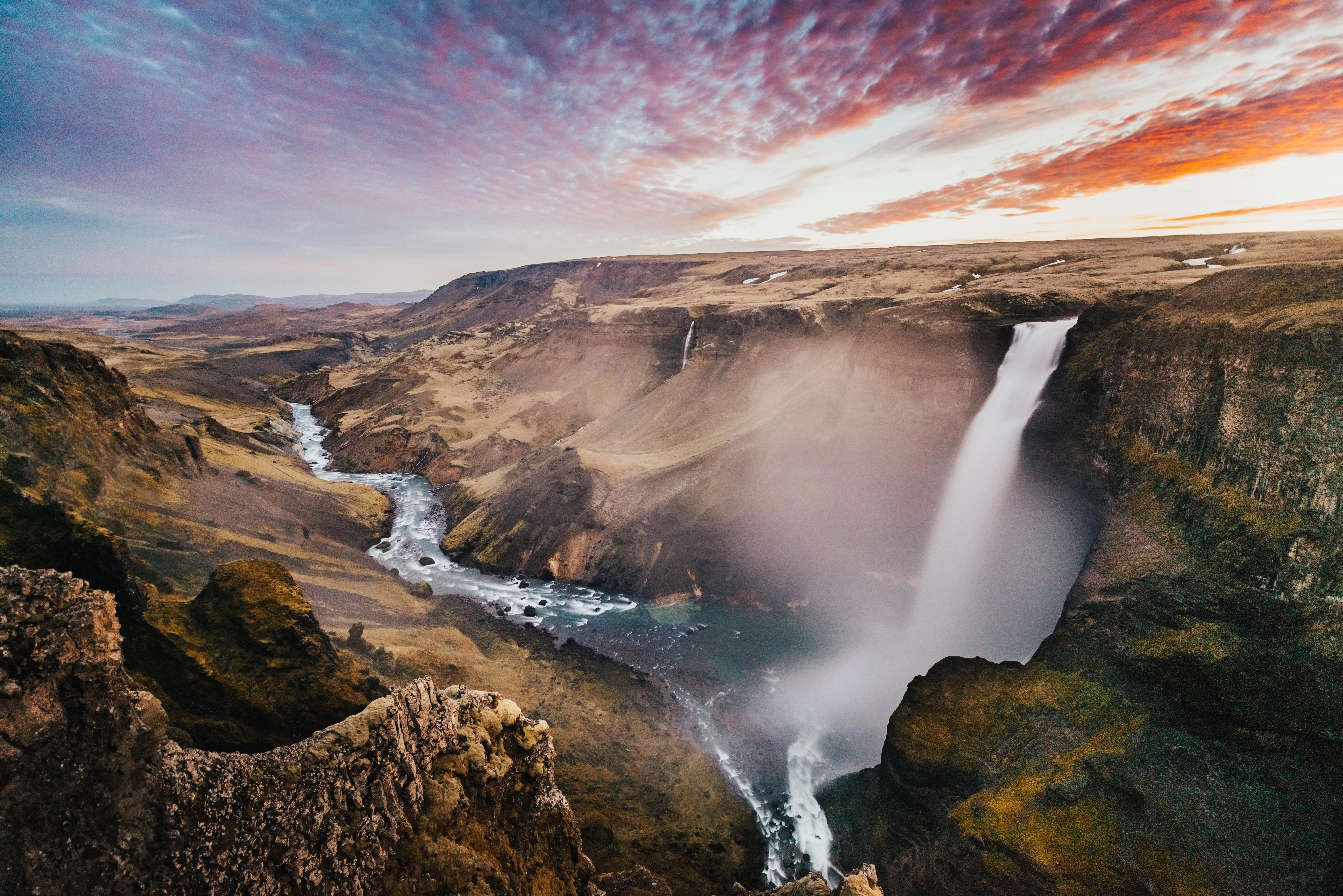 Waterfall cascading into canyon at golden hour image
