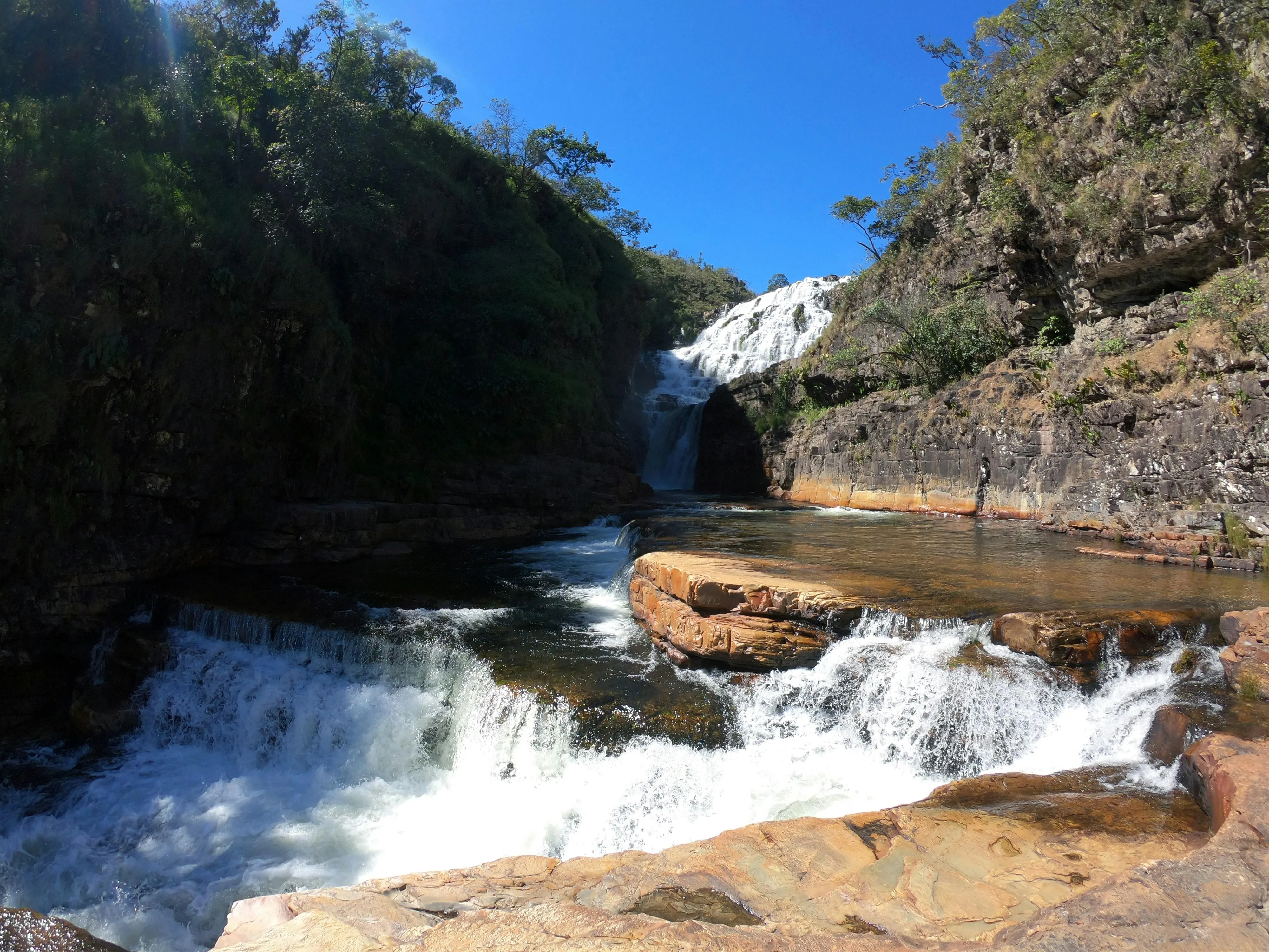 Waterfall Flowing over Rocks into Forest River image