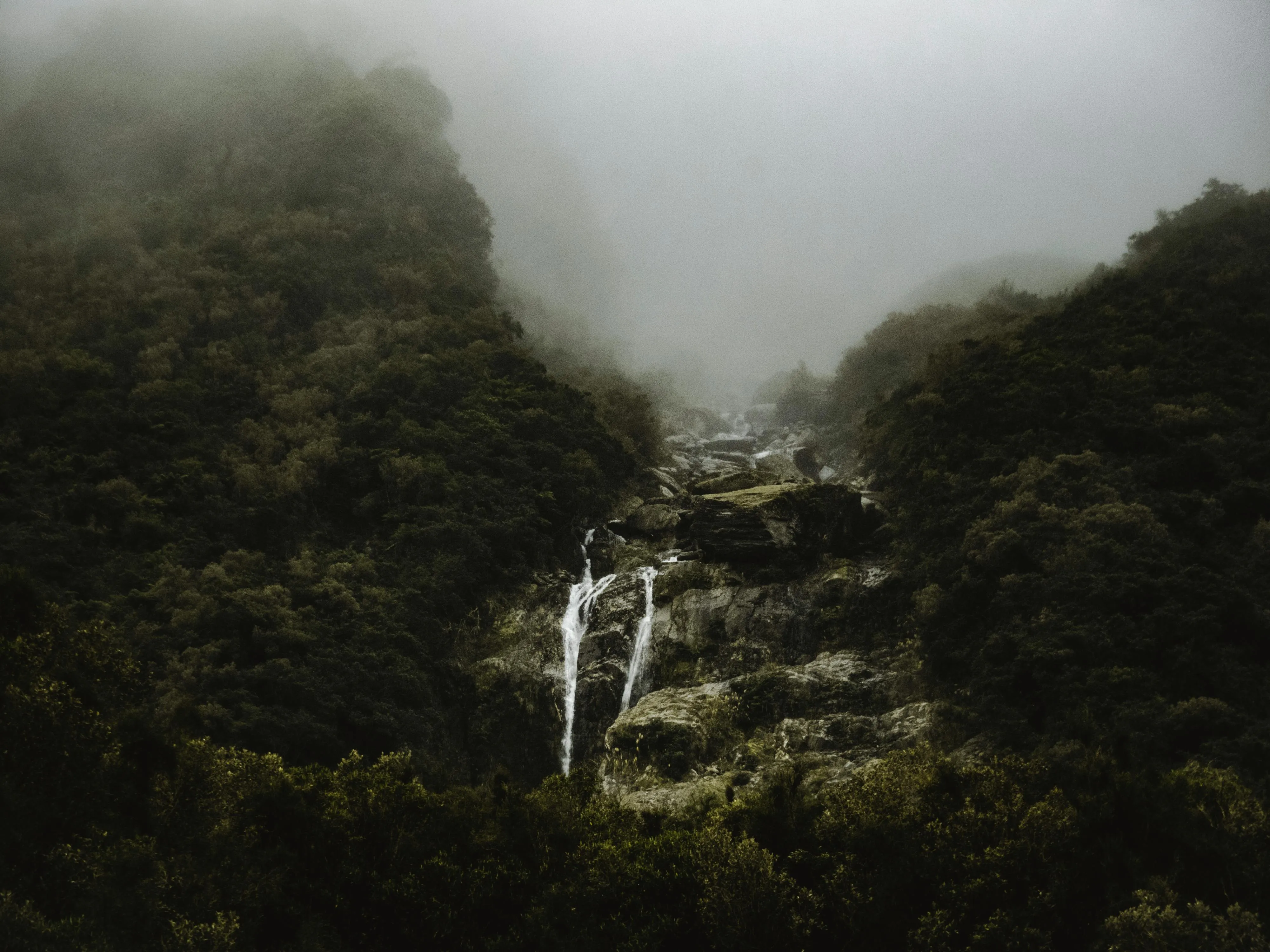 Waterfall Flowing Through a Misty Forest in the Mountains