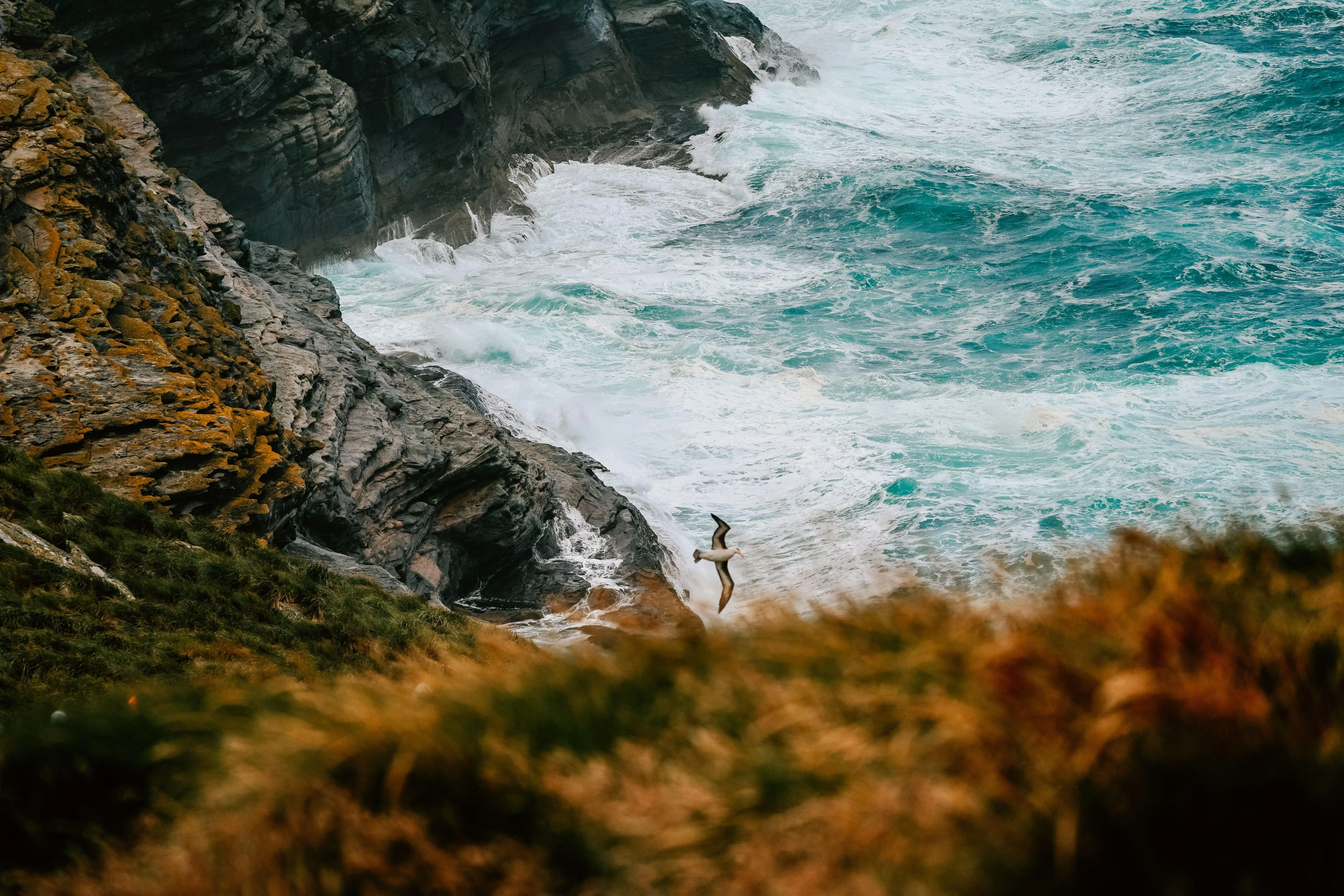 Waves crashing on rocky coastal cliffs with mist rising