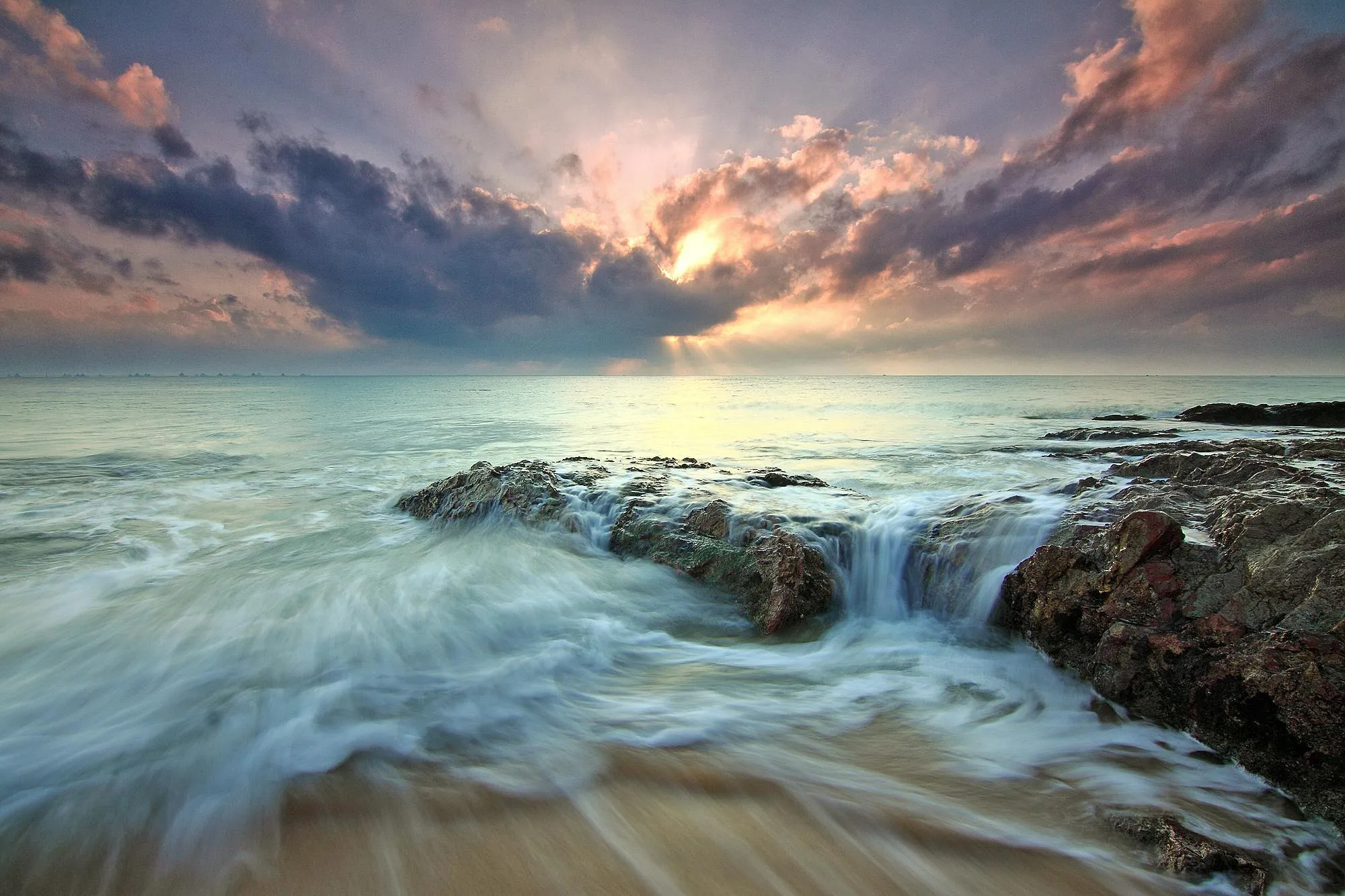 Waves Smash Against Rocks at Sunset with Storm Clouds