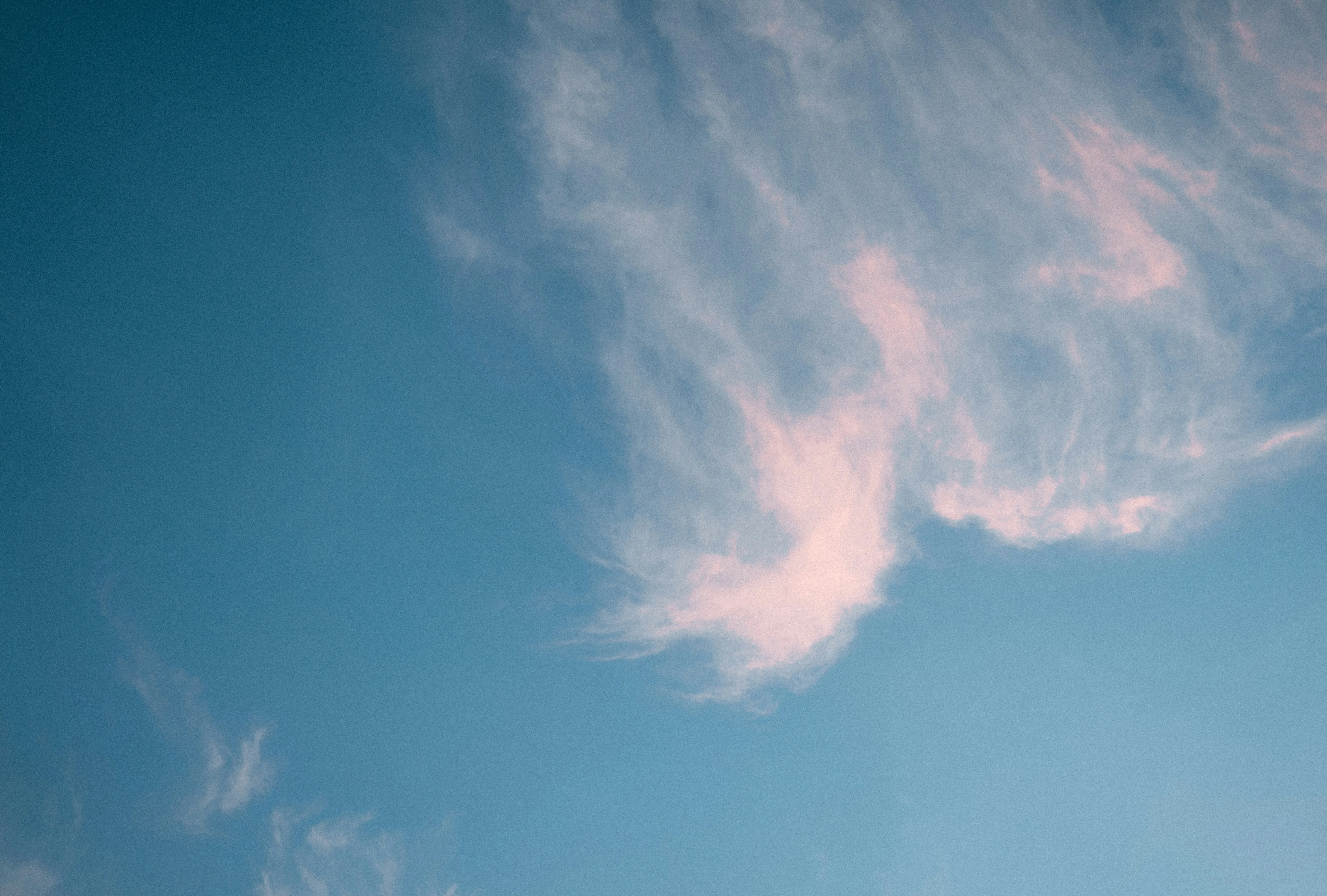 Whispy Pink Clouds Floating in a Clear Blue Sky Wallpaper
