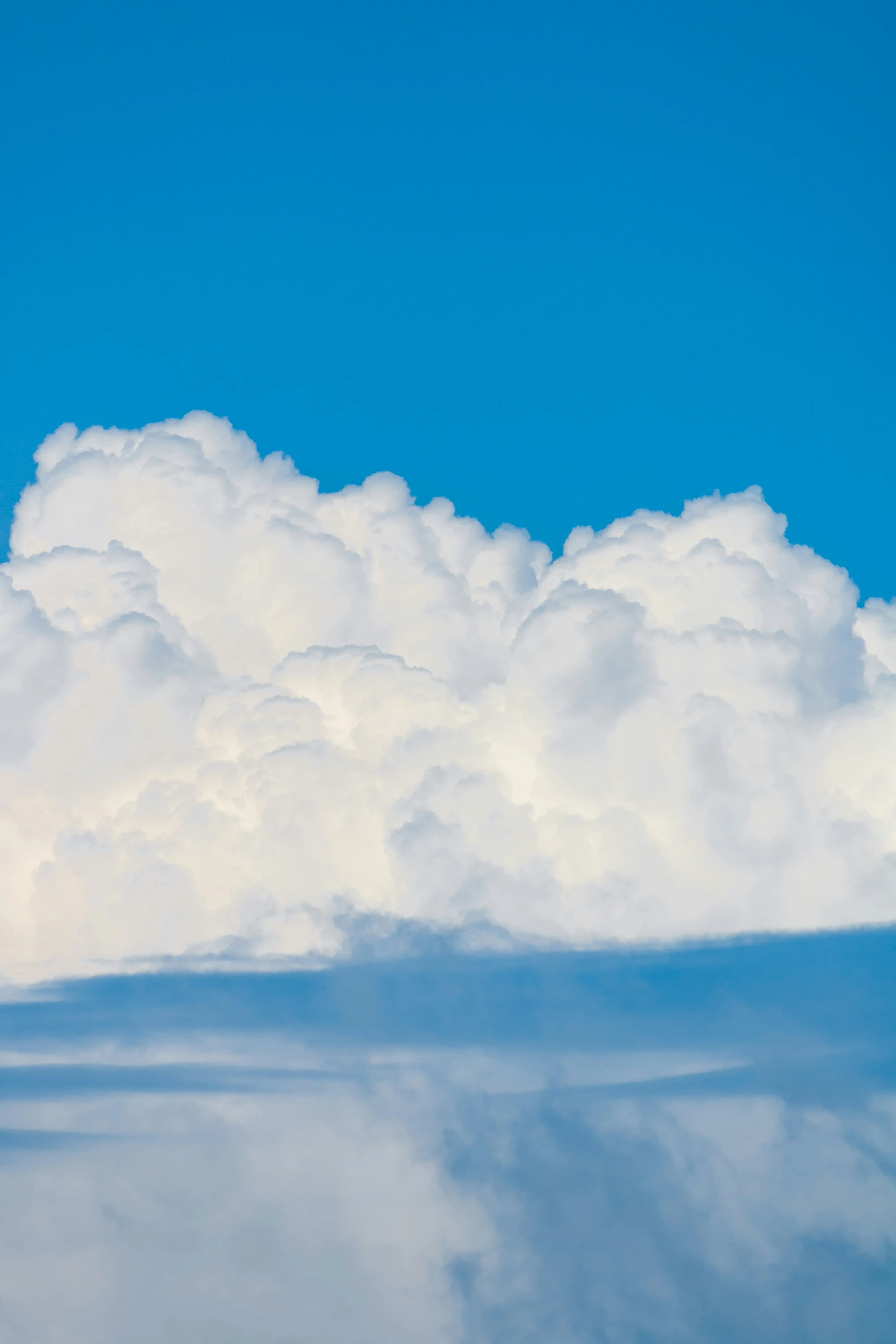 White Clouds Rising Above Mountain Peaks in Clear Sky