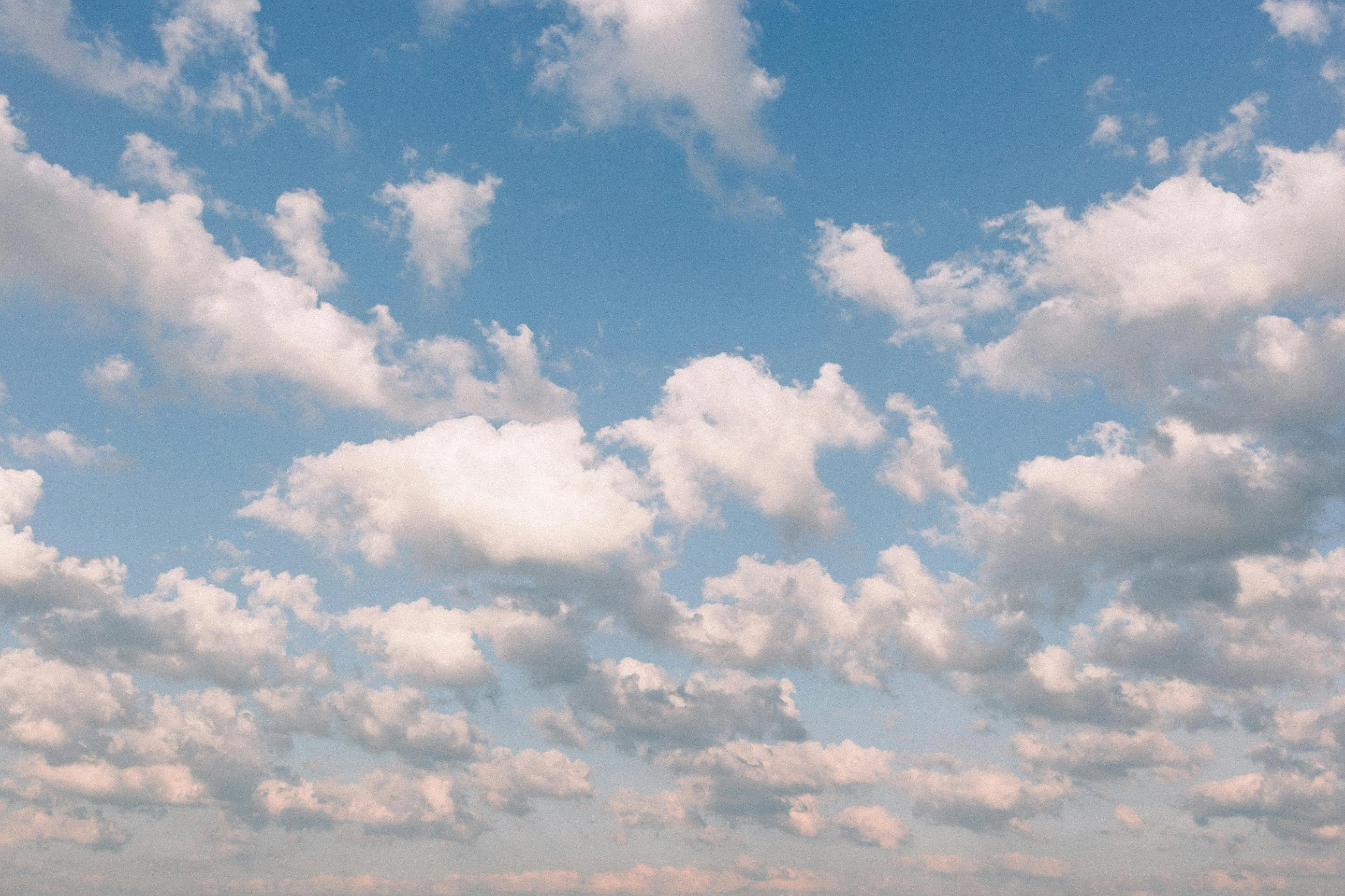 White Puffy Clouds Floating Over Bright Blue Sky in Daylight