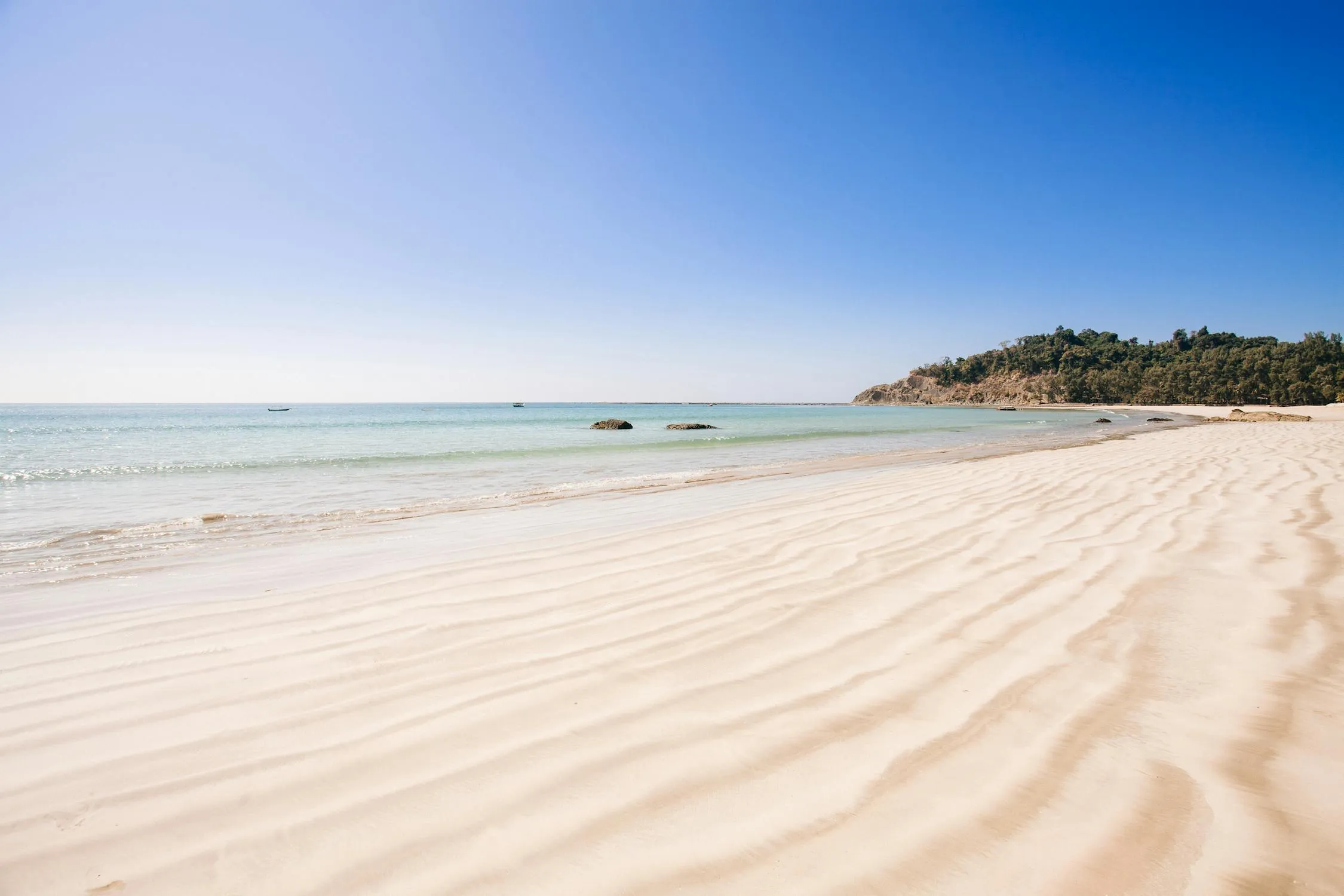 White Sandy Beach Under Clear Blue Sky with Ocean Horizon