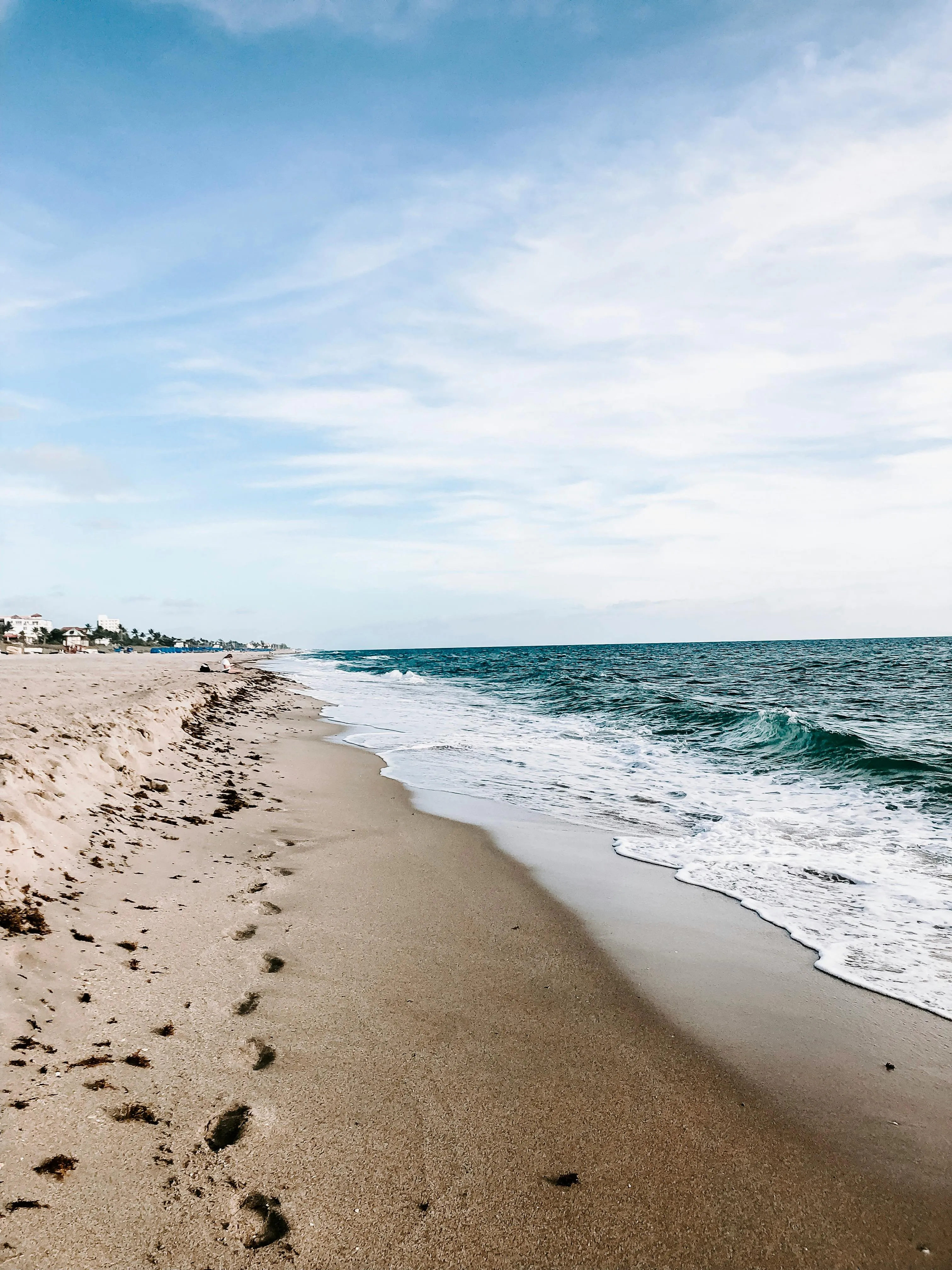 White Waves Crashing Under Clear Sky with Beach Clouds