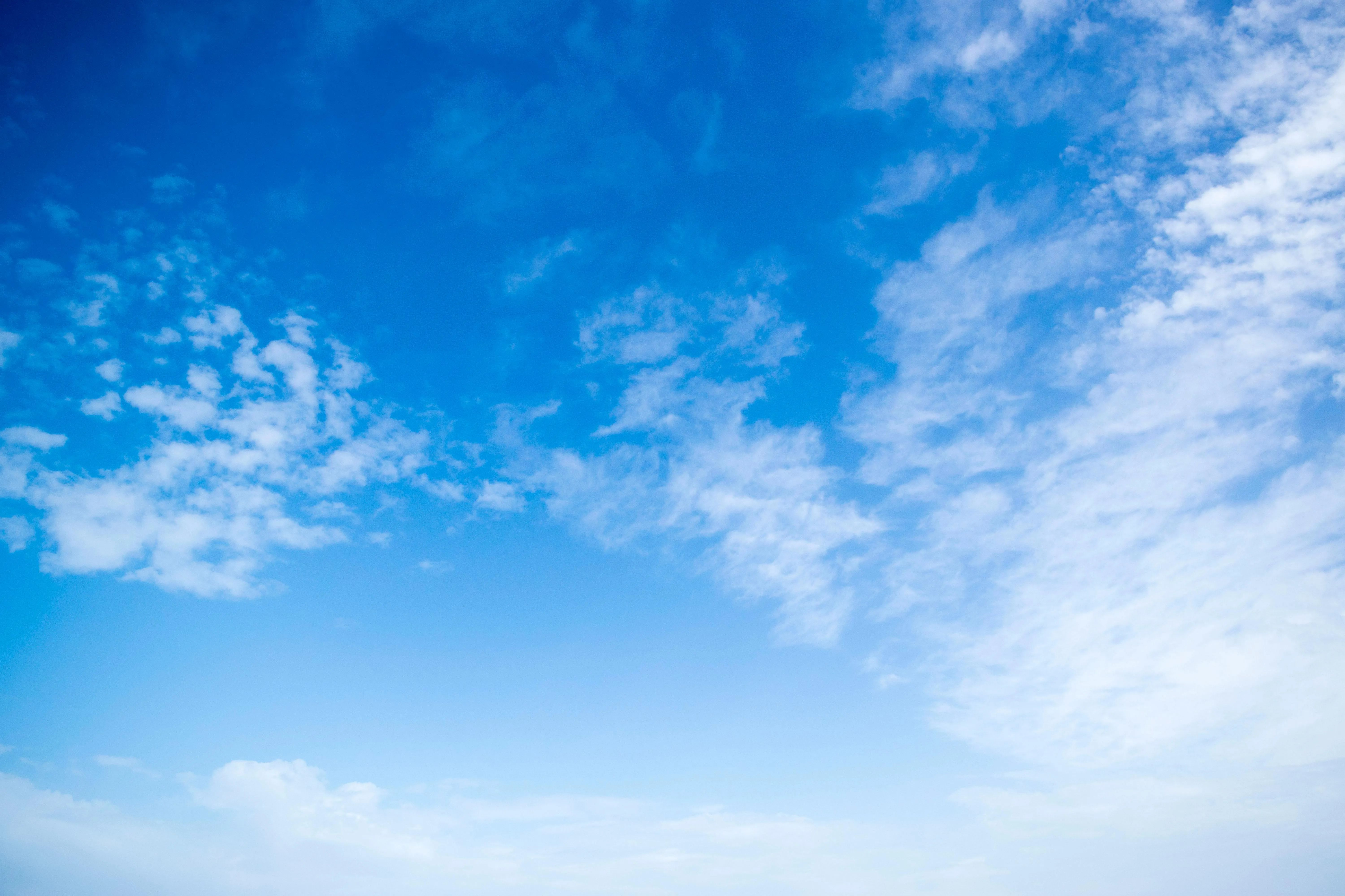 Wide Blue Sky with Scattered Wispy Clouds Above Mountains