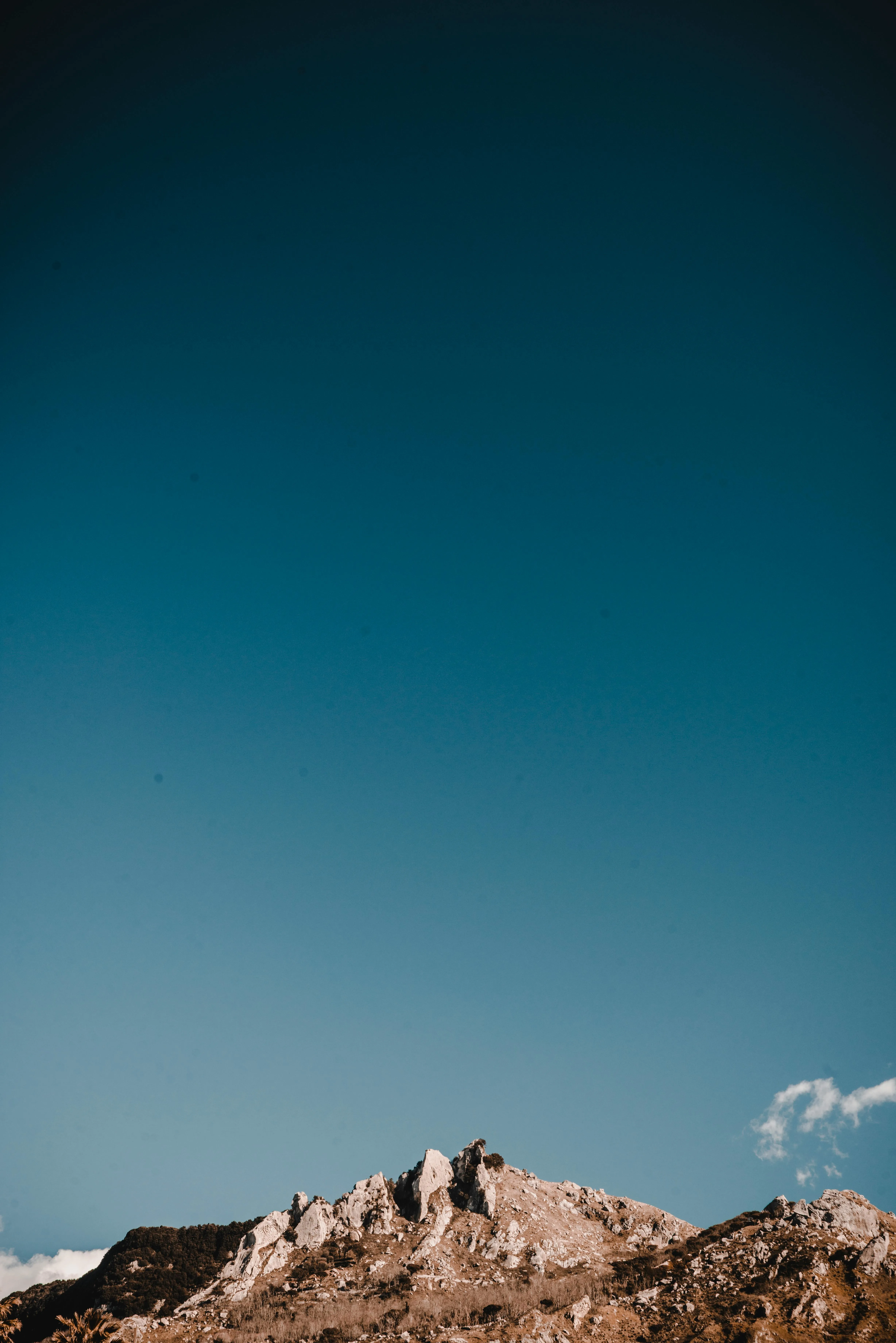 Wide View of Hill Against a Deep Teal Blue Sky Wallpaper