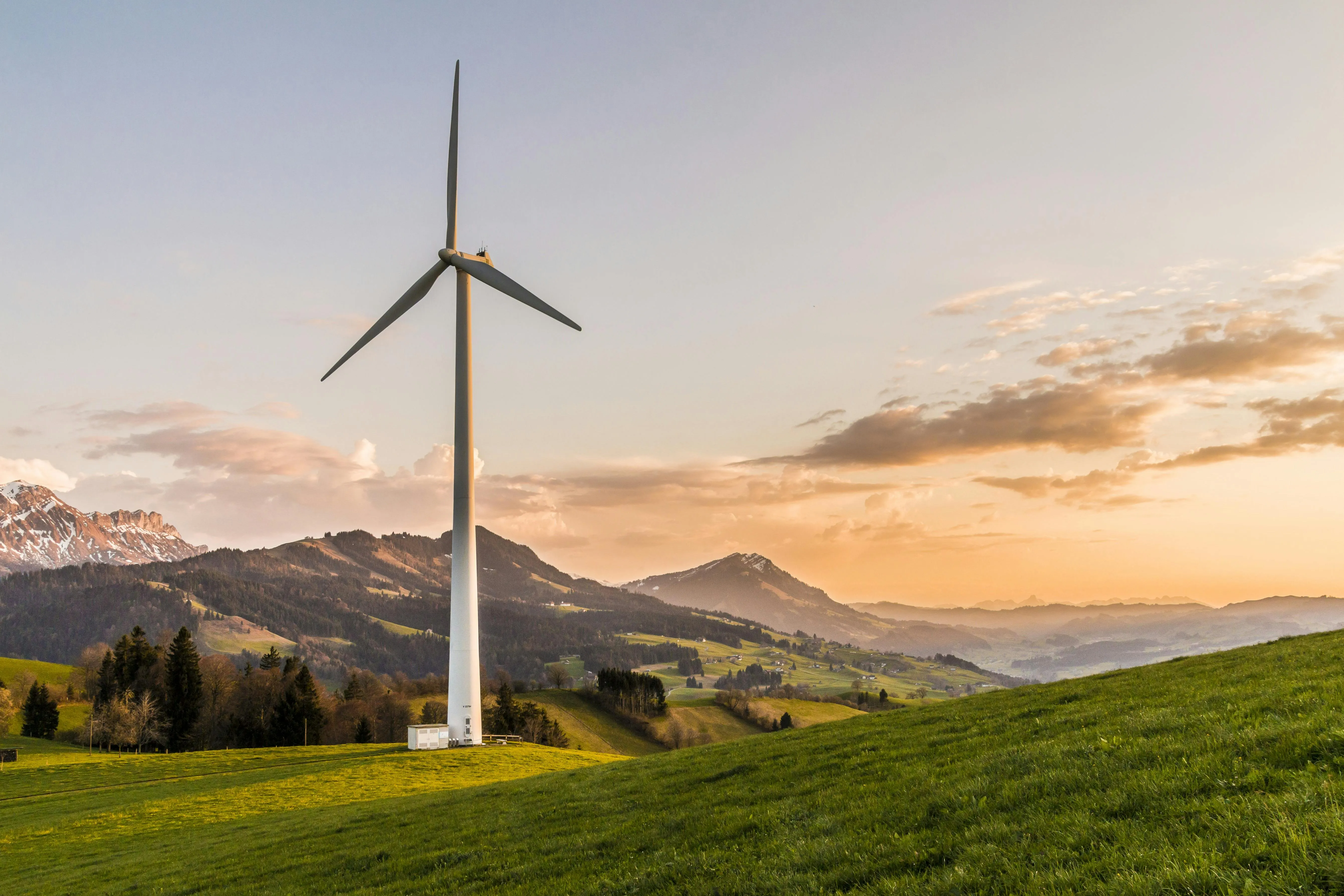 Wind Turbine Under Golden Sky with Soft Mountain Clouds