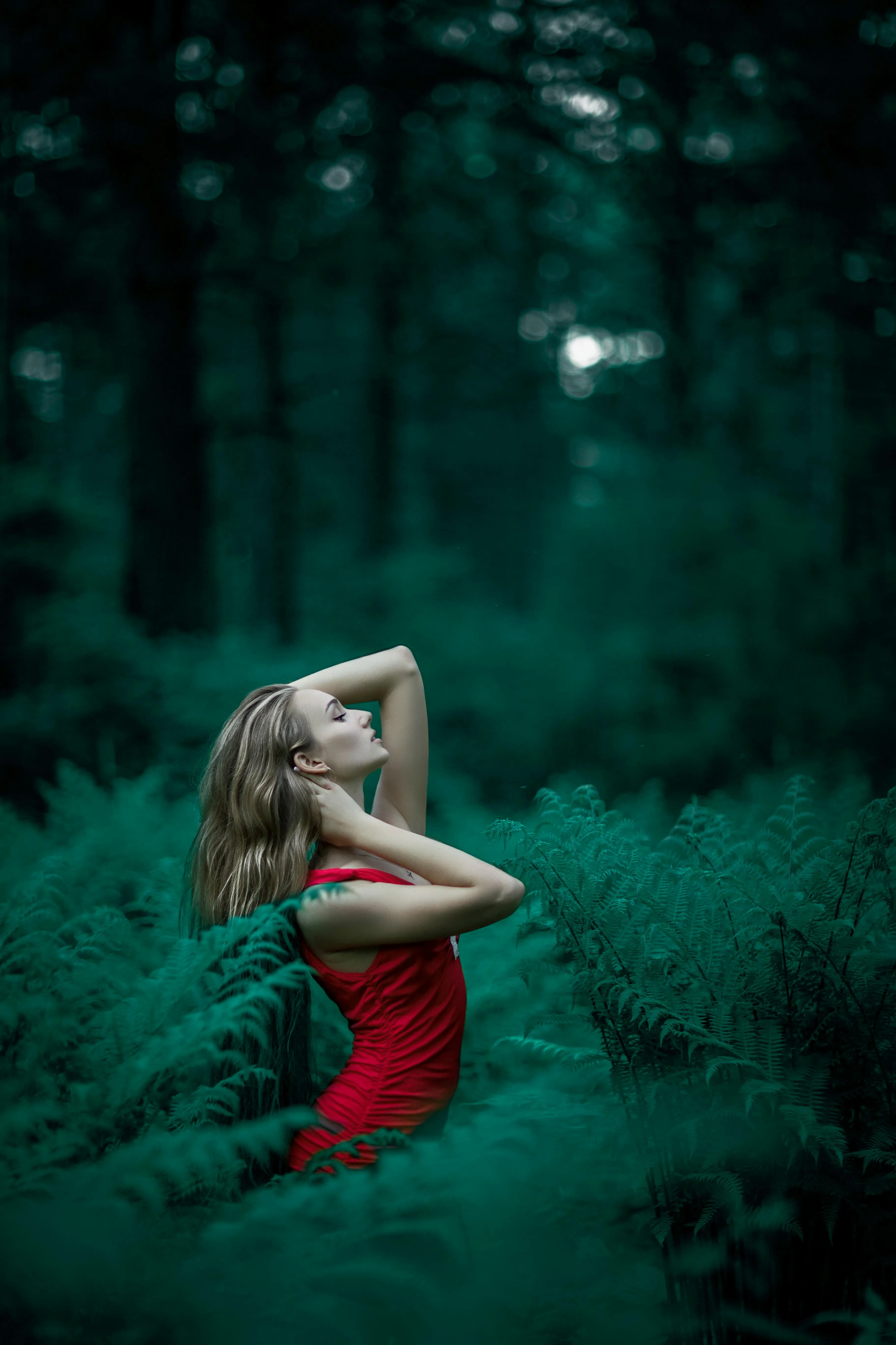 Woman in a Red Dress Sitting Alone in a Deep Green Forest