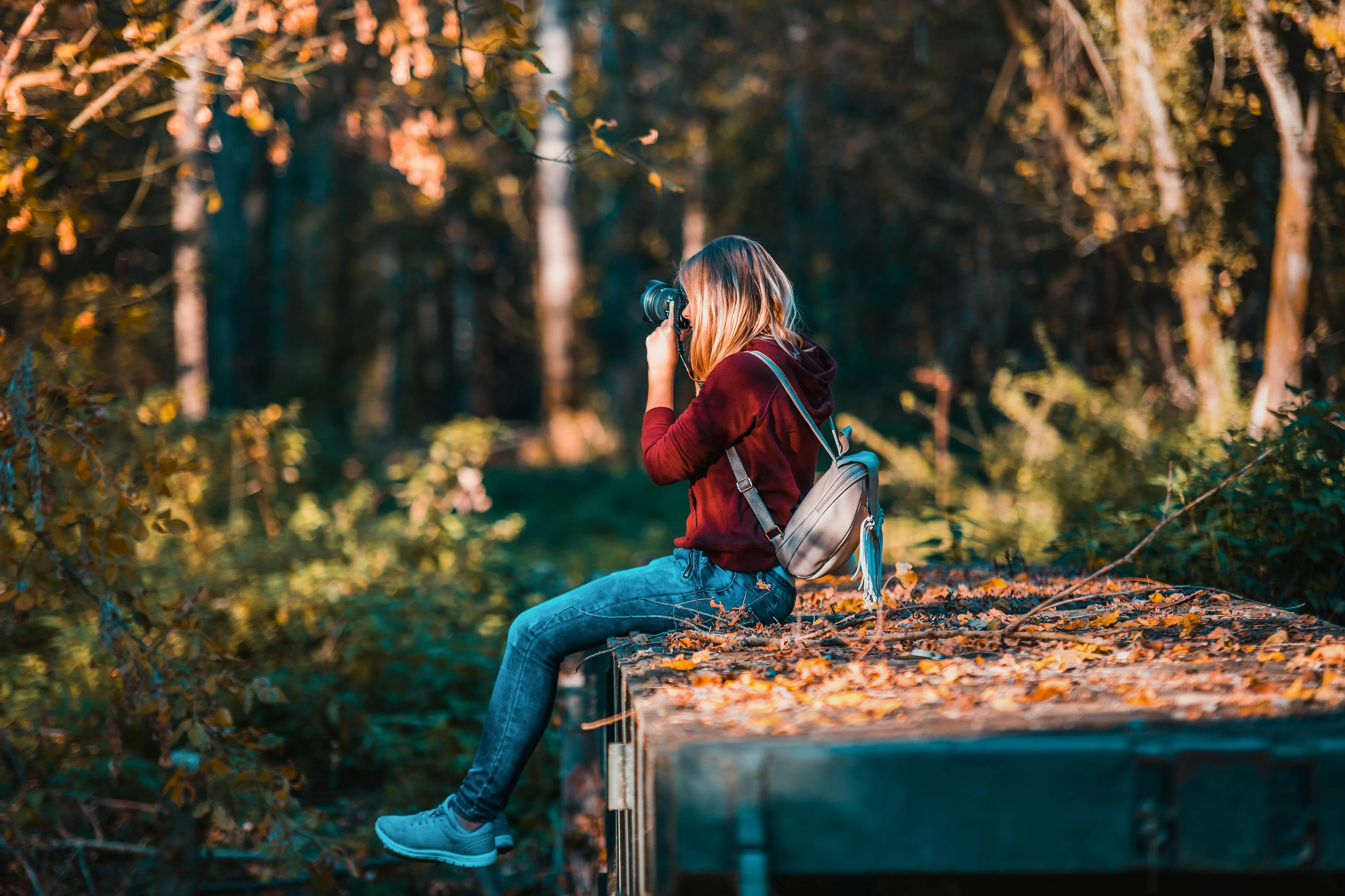Woman Sitting in an Autumn Forest with Falling Leaves