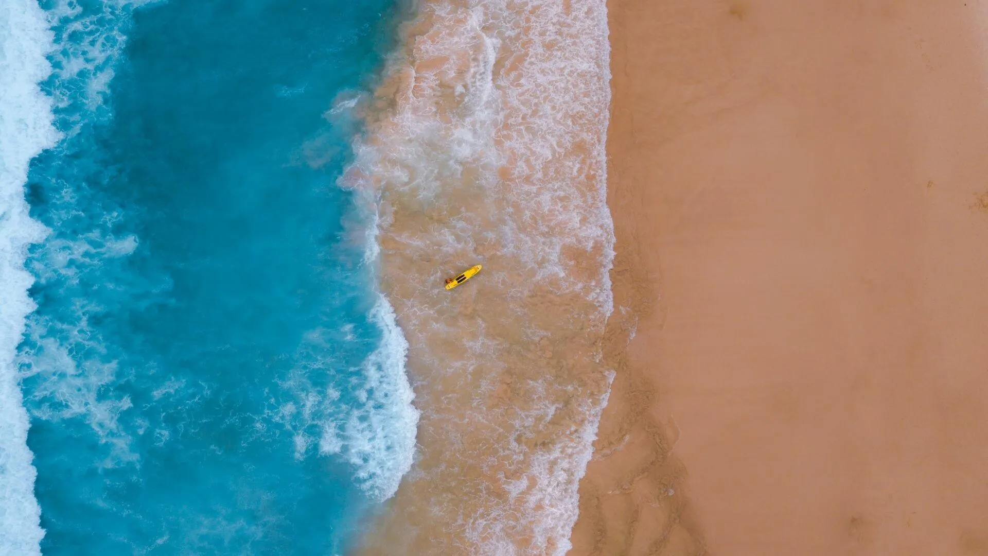 Aerial View of Waves Meeting the Golden Sandy Shoreline